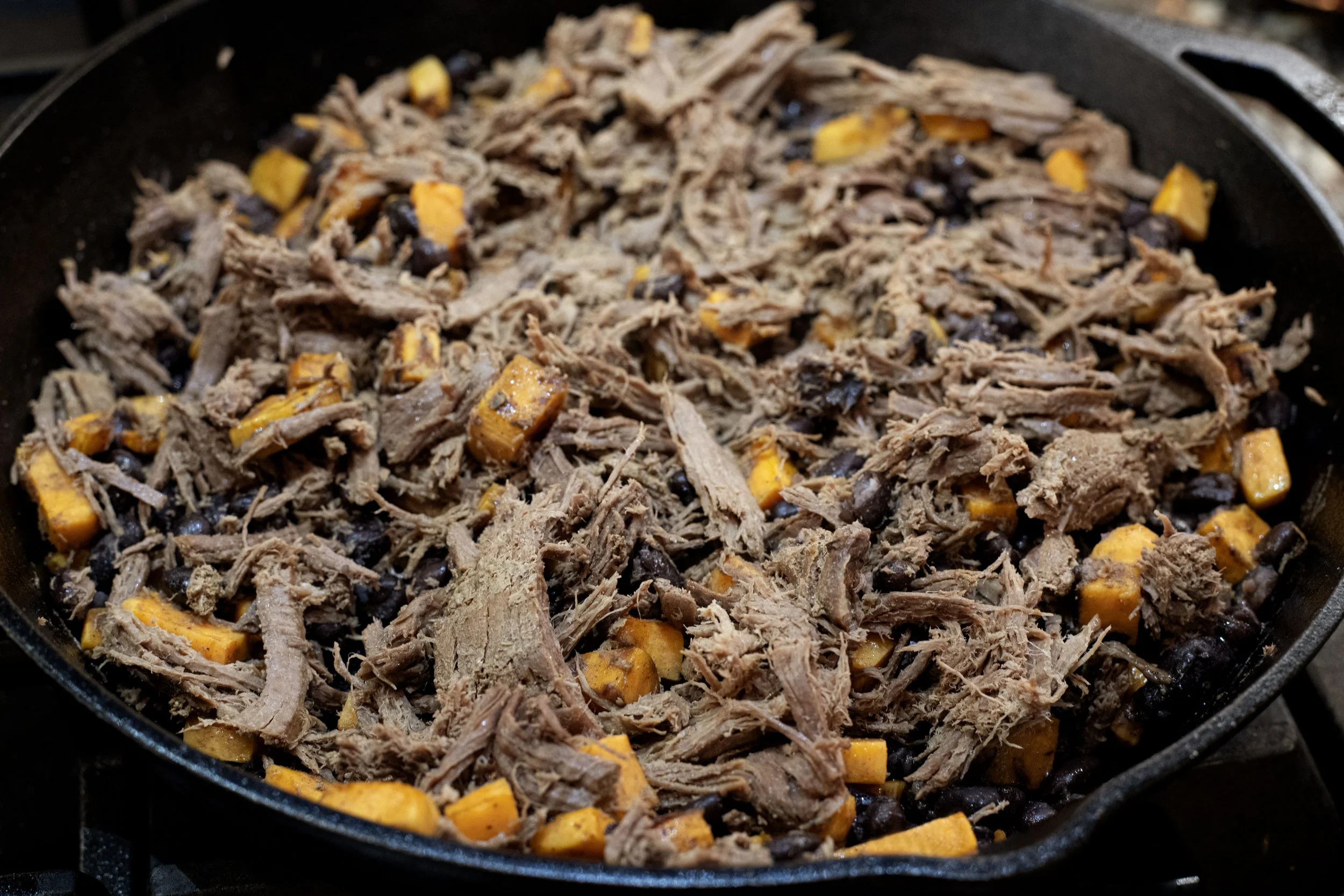 Shredded venison meat over sweet potatoes and beans for tacos