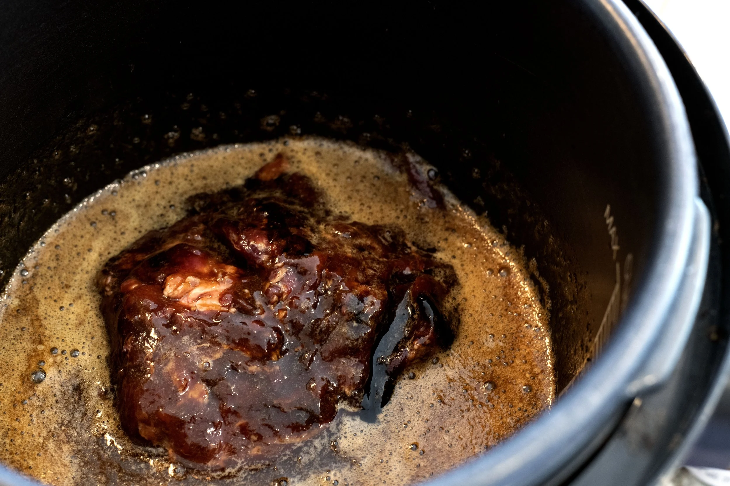 Javelina meat sit in a pressure cooker surrounded by braising liquid