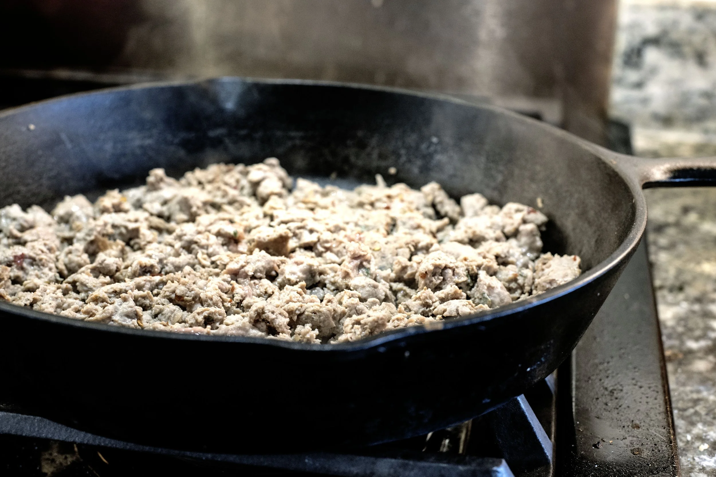 Ground Pheasant sausage browning in a heavy cast iron skillet