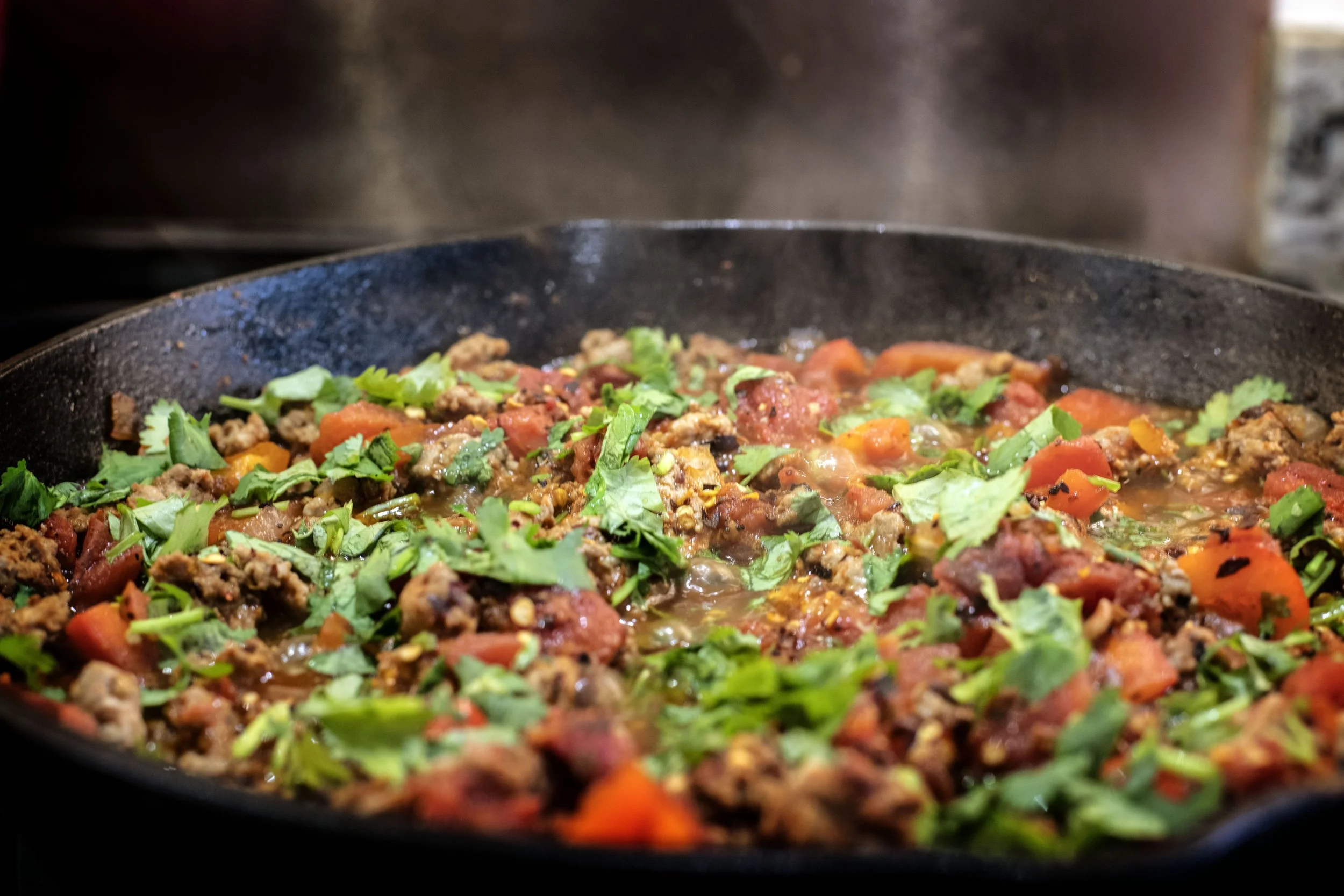 shakshuka taco meat with green kale and cilantro on top and fire roasted tomatoes with red bell pepper