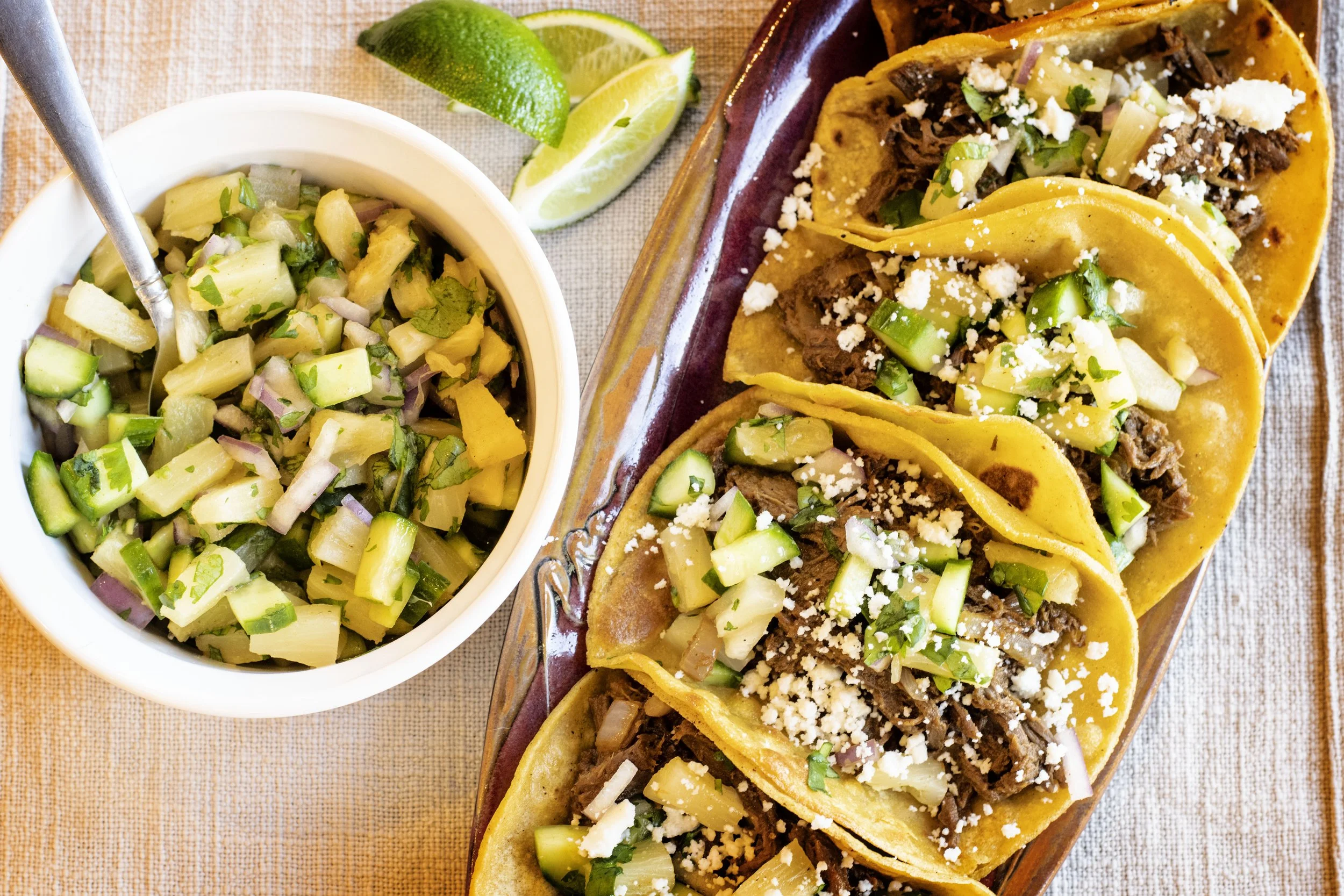 A plate of four tacos filled with apricot venison and served with a side of pineapple salsa