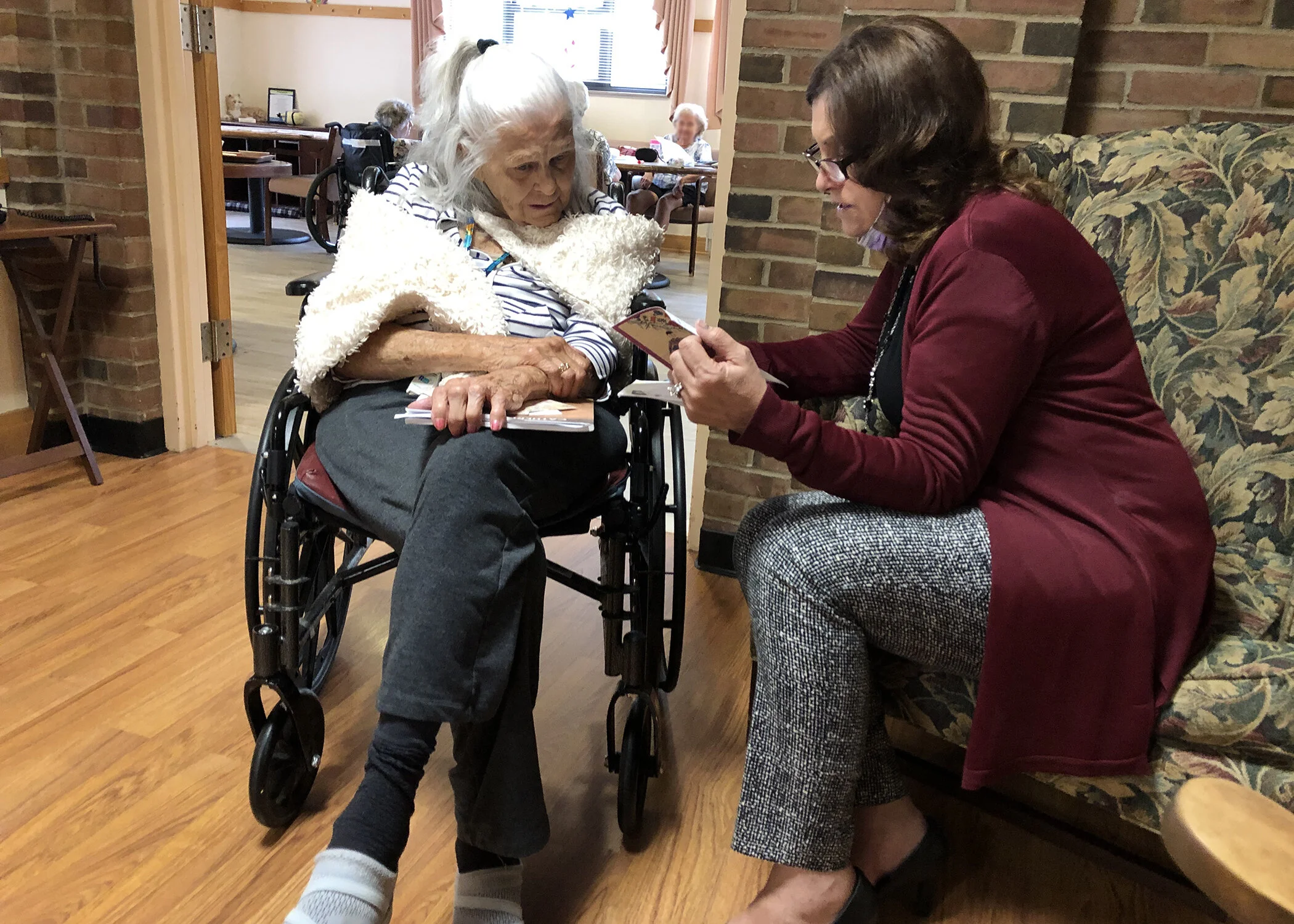 Administrator Diane Ott helps resident Stephanie Dumser read greeting cards she recently received. Mail has been a welcome connection with family during isolation.