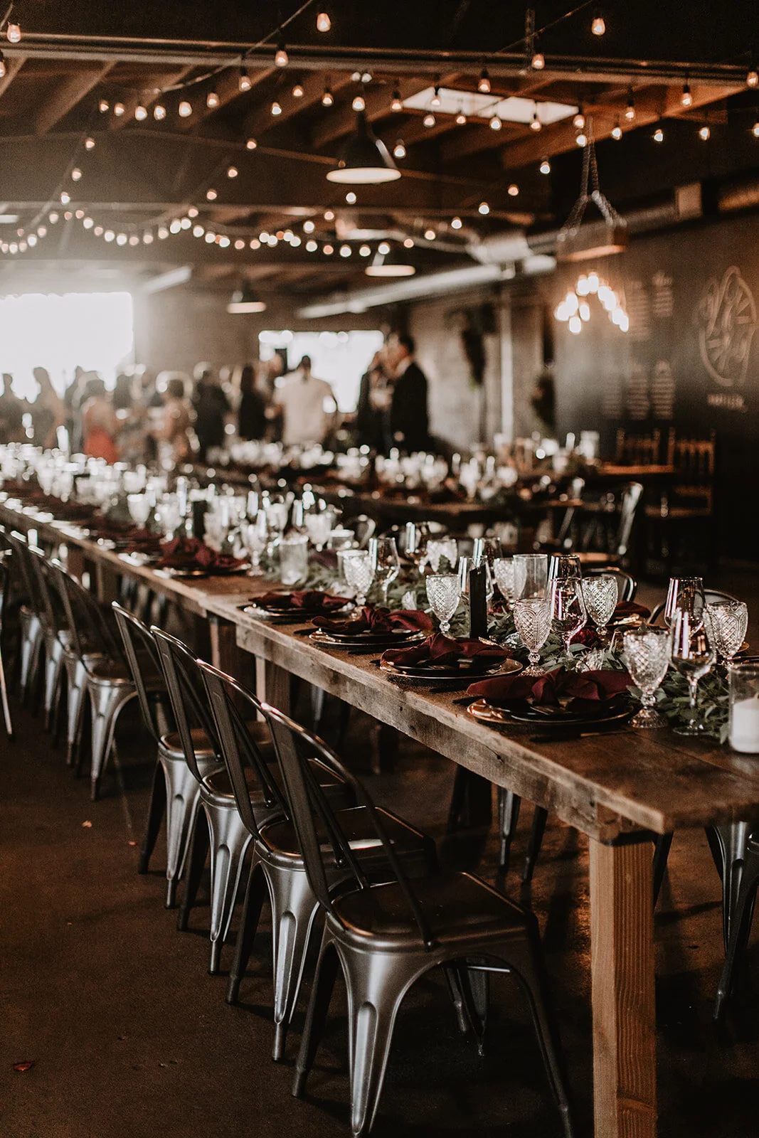 Family style seating with bistro chairs and string lights at warehouse wedding in Los Angeles