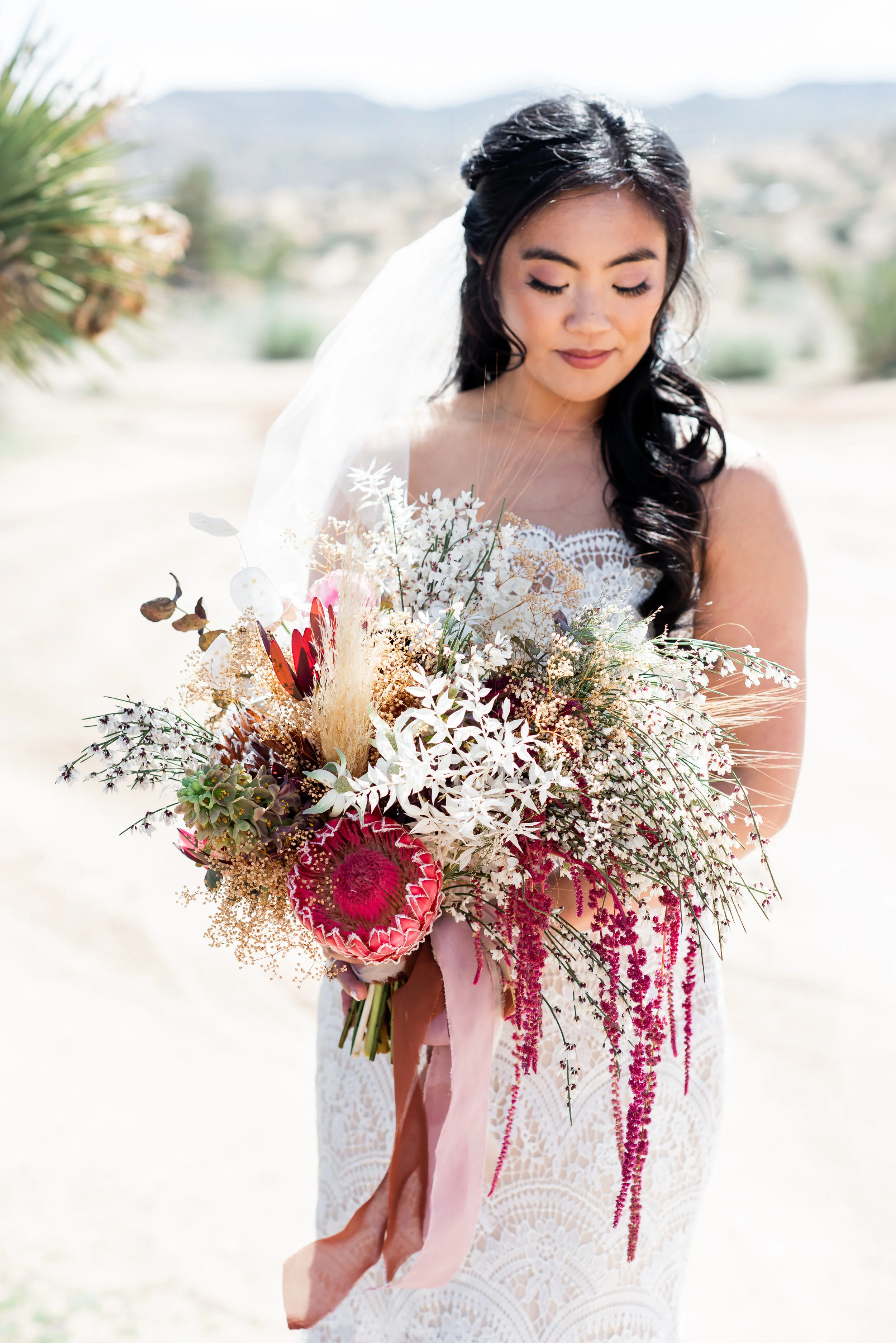  I love the movement in this bouquet! There’s so many special blooms here - protea, flannel flower, butterfly ranunculus - but it’s the textures of grasses, ruscus, and amaranthus that make the magic.  Photography Stephanie Ann Weddings 