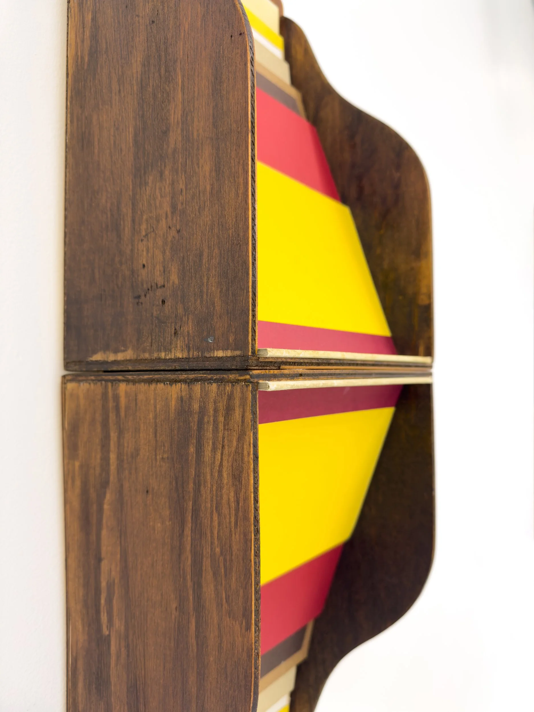 Wooden shelves viewed from the side display vibrant yellow, red, and beige panels, creating a modern, abstract design with a warm, artistic tone.