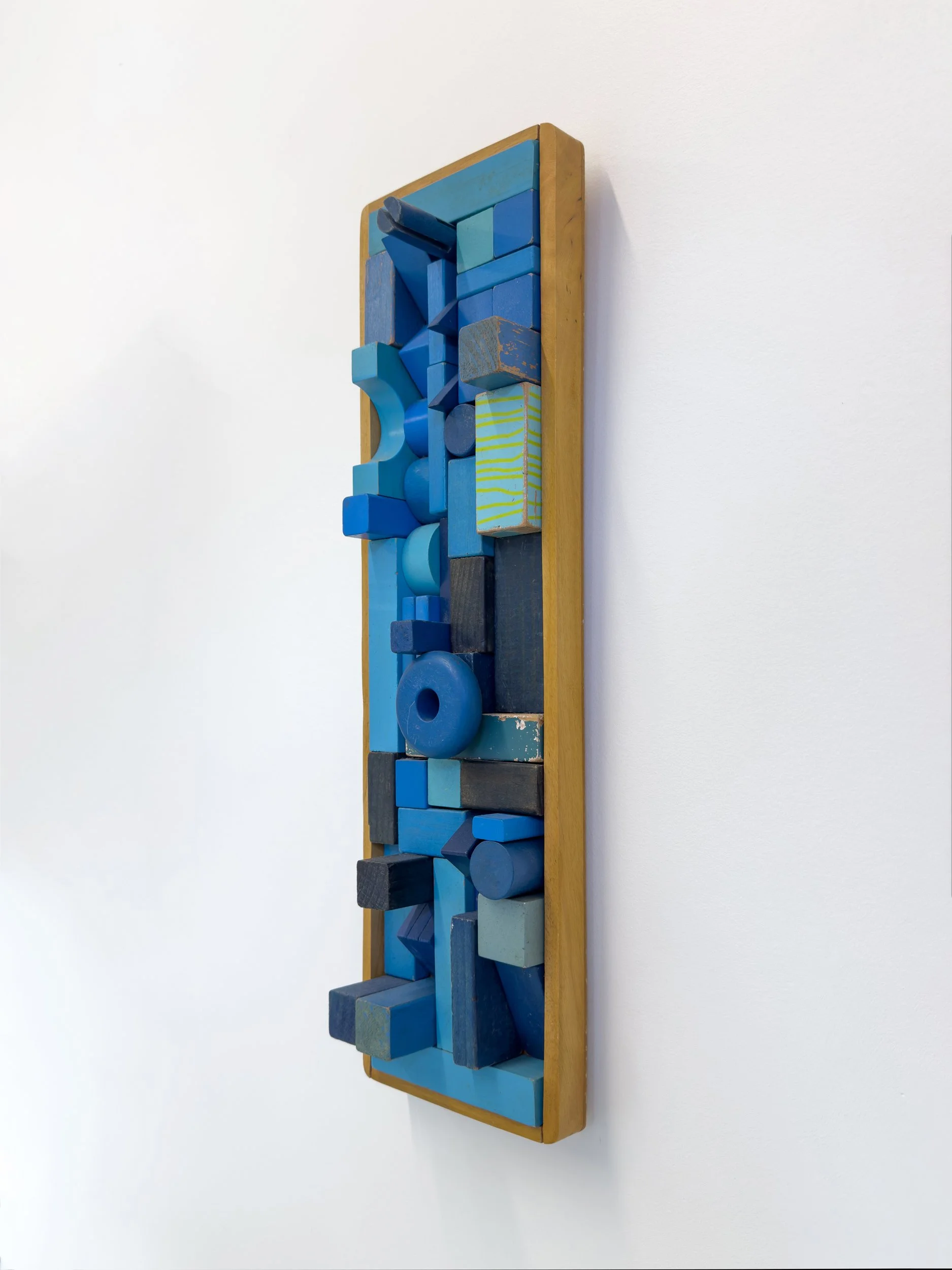 Vertical abstract art piece with a wooden frame, featuring blue geometric shapes of varying sizes and shades. Modern and minimalist design.