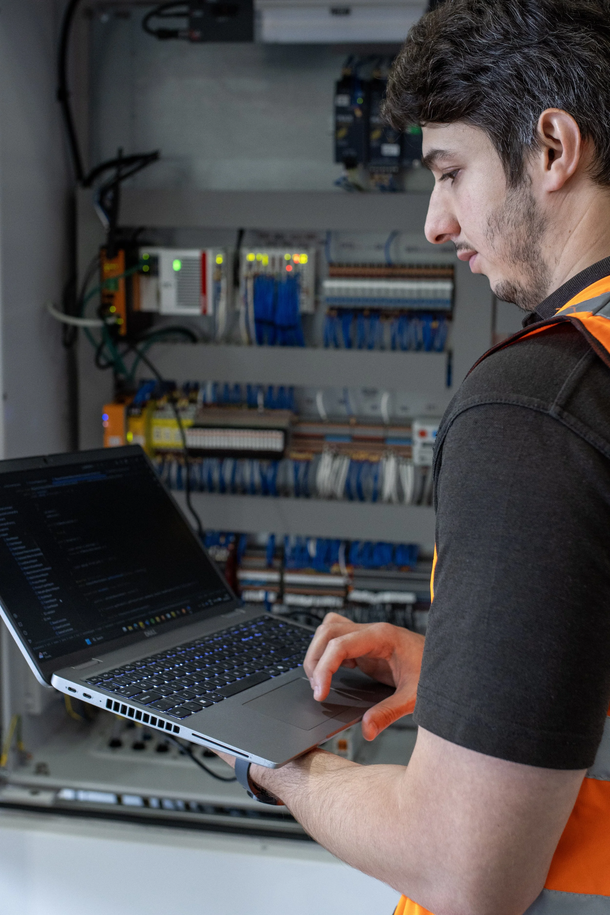 Man in front of brick wall wearing a Hollister T-shirt, arms crossed