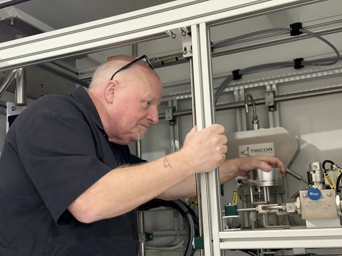 Portrait of an older man with a beard wearing a dark shirt, against a white background.