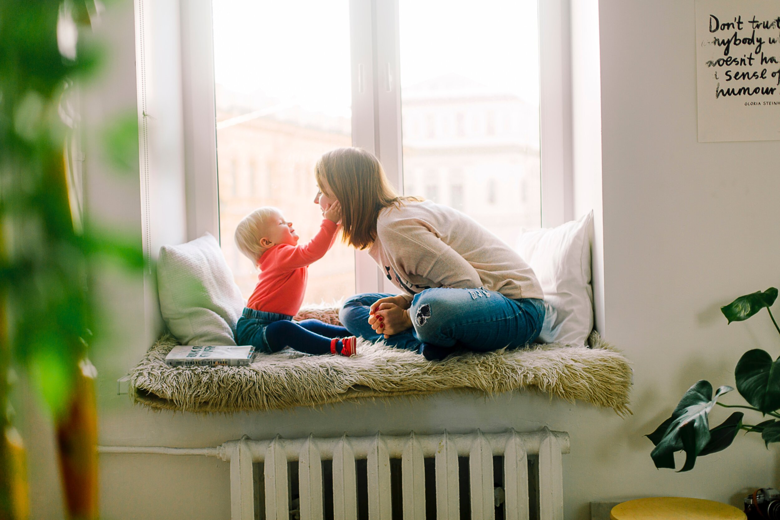 Woman and baby playing in window sill