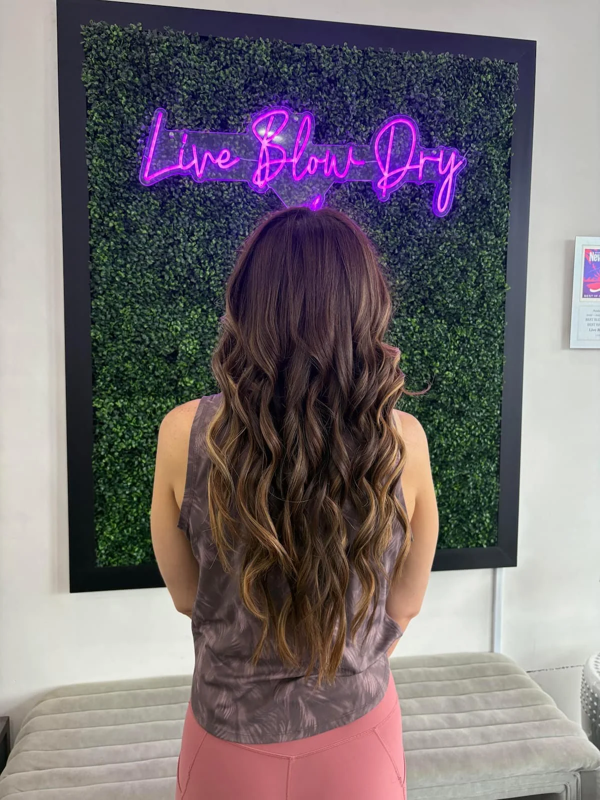 Long wavy blowout photographed at the Live Blow Dry greenery wall