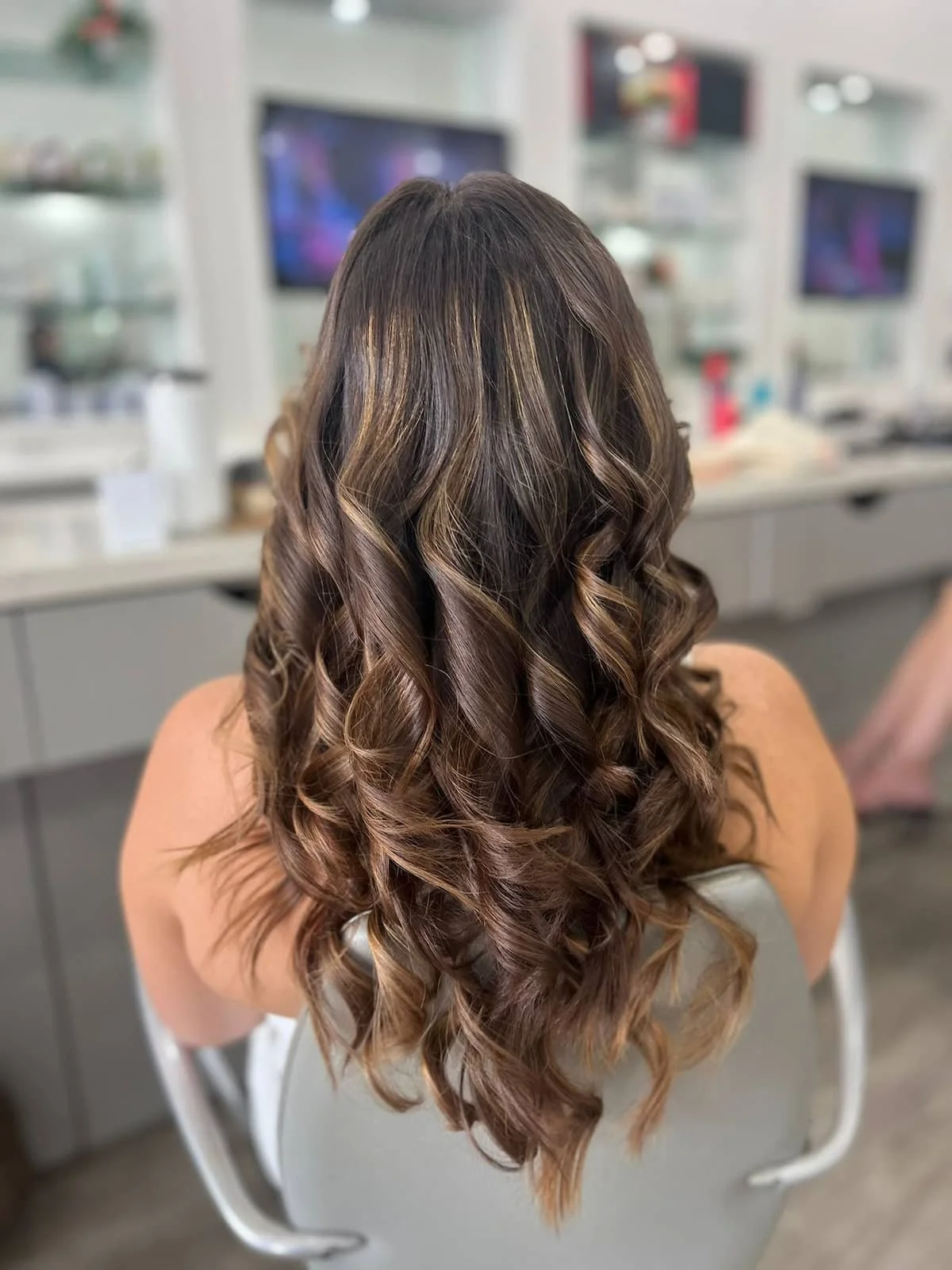 Back view of a curly blowout with blonde highlights styled in the salon