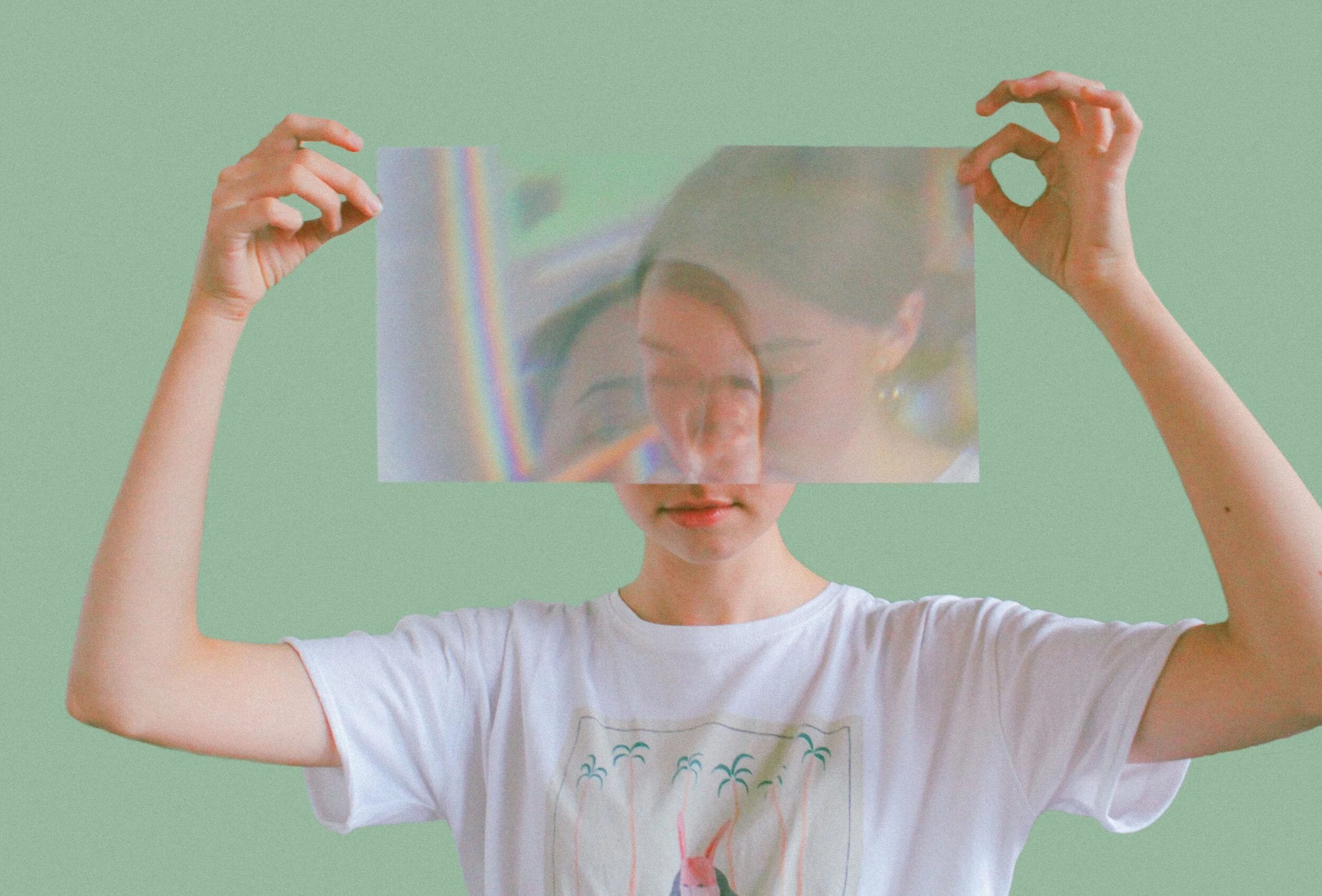  A woman holds a reflective sheet in front of her face, so it reflects from different angles. 