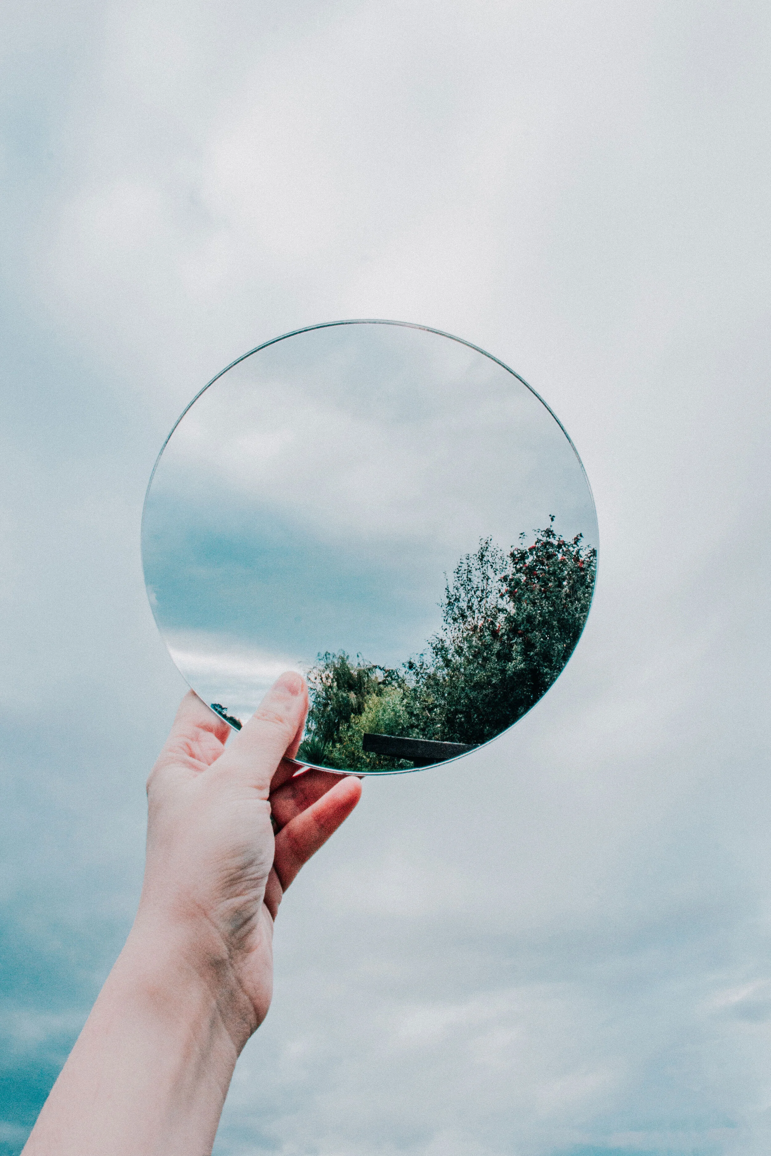 A magnifying disc held up to a partially clear blue sky