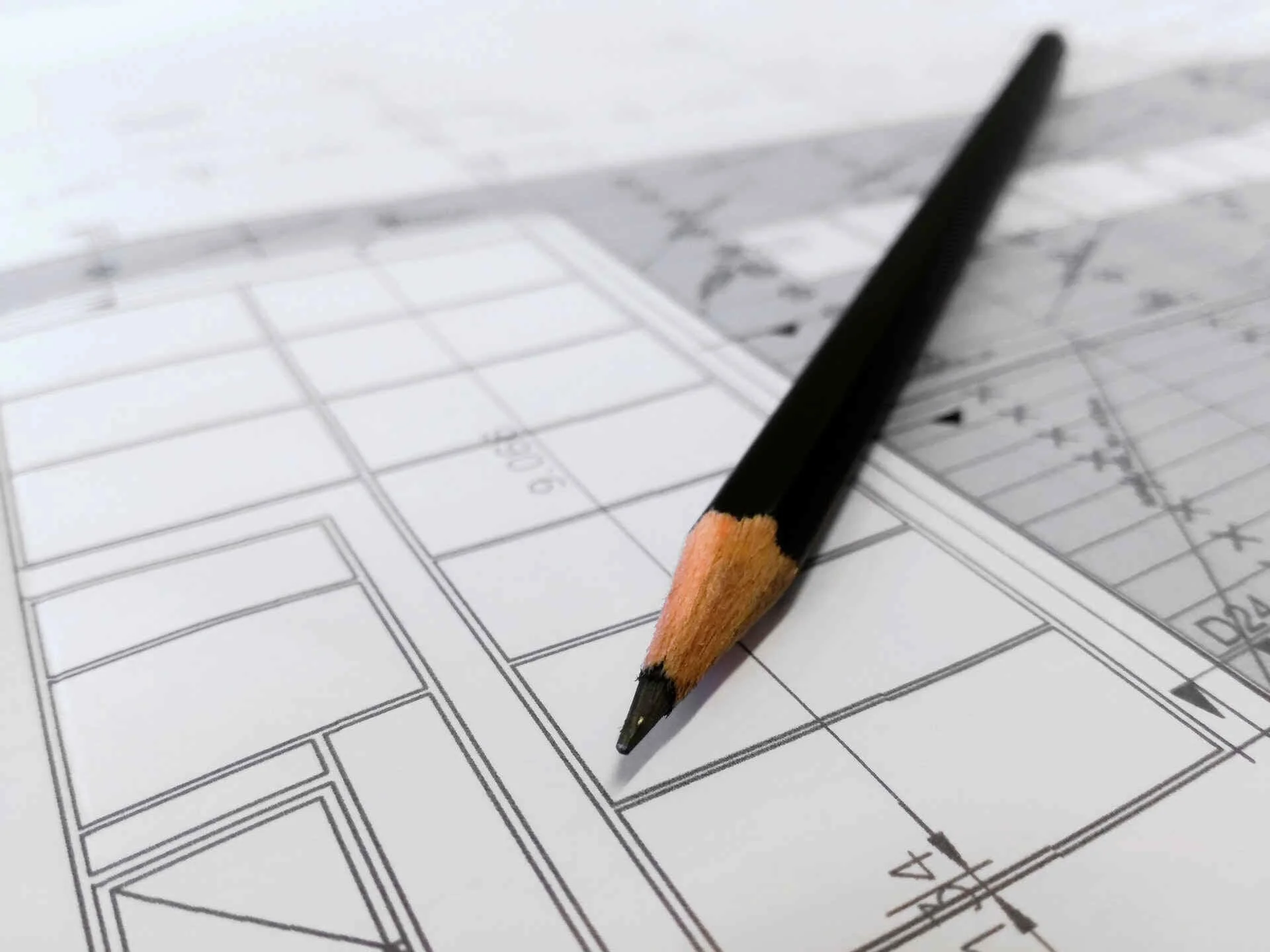 Paper with architectural plans and a pensil on top.
