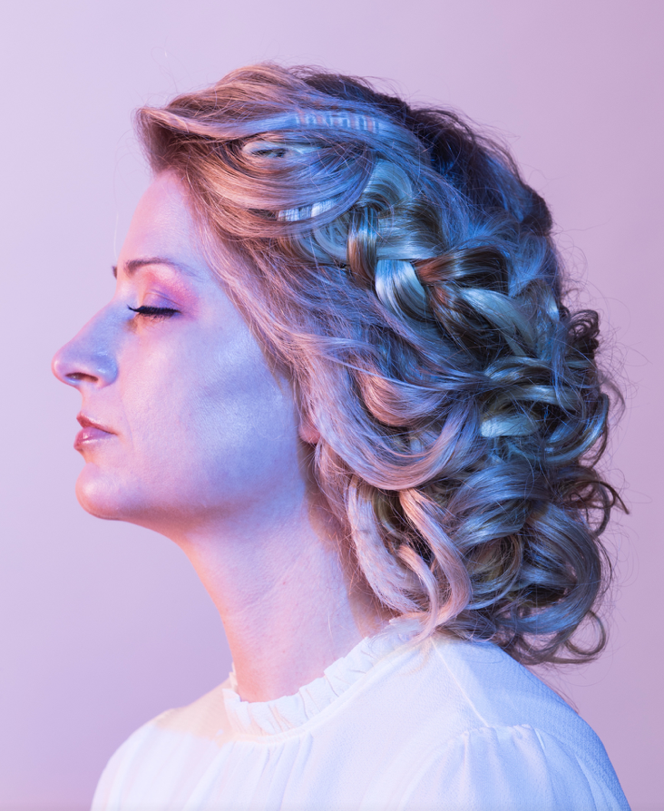 Braided editorial hairstyle with pastel blue and pink lighting.