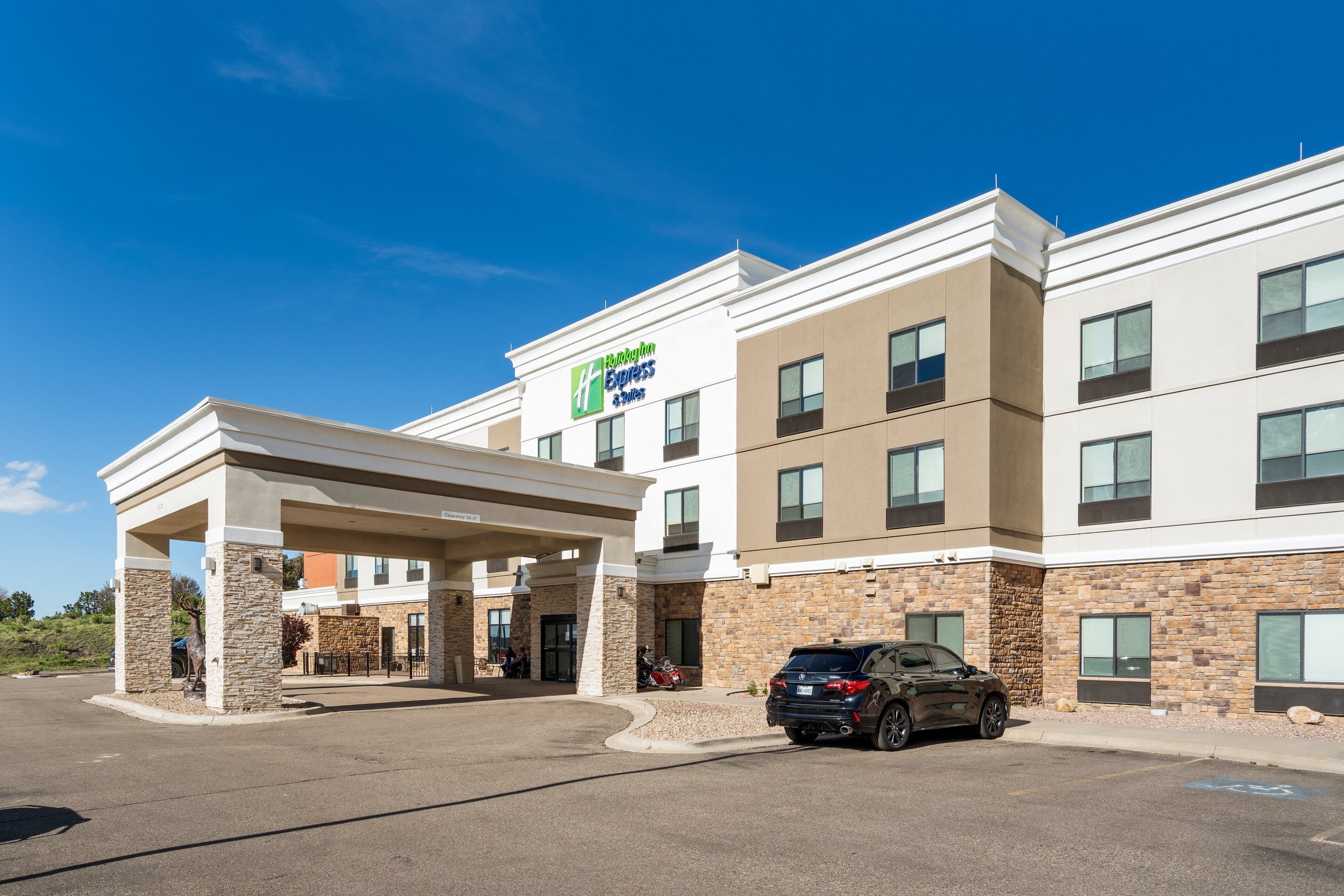 Holiday Inn Express hotel exterior with parking lot and cars, under a clear blue sky.