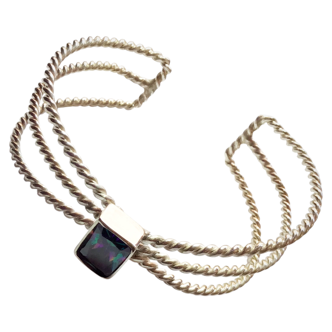 This amazing brazalet is the path of interwined precious circuits to end in an every colored gem. 