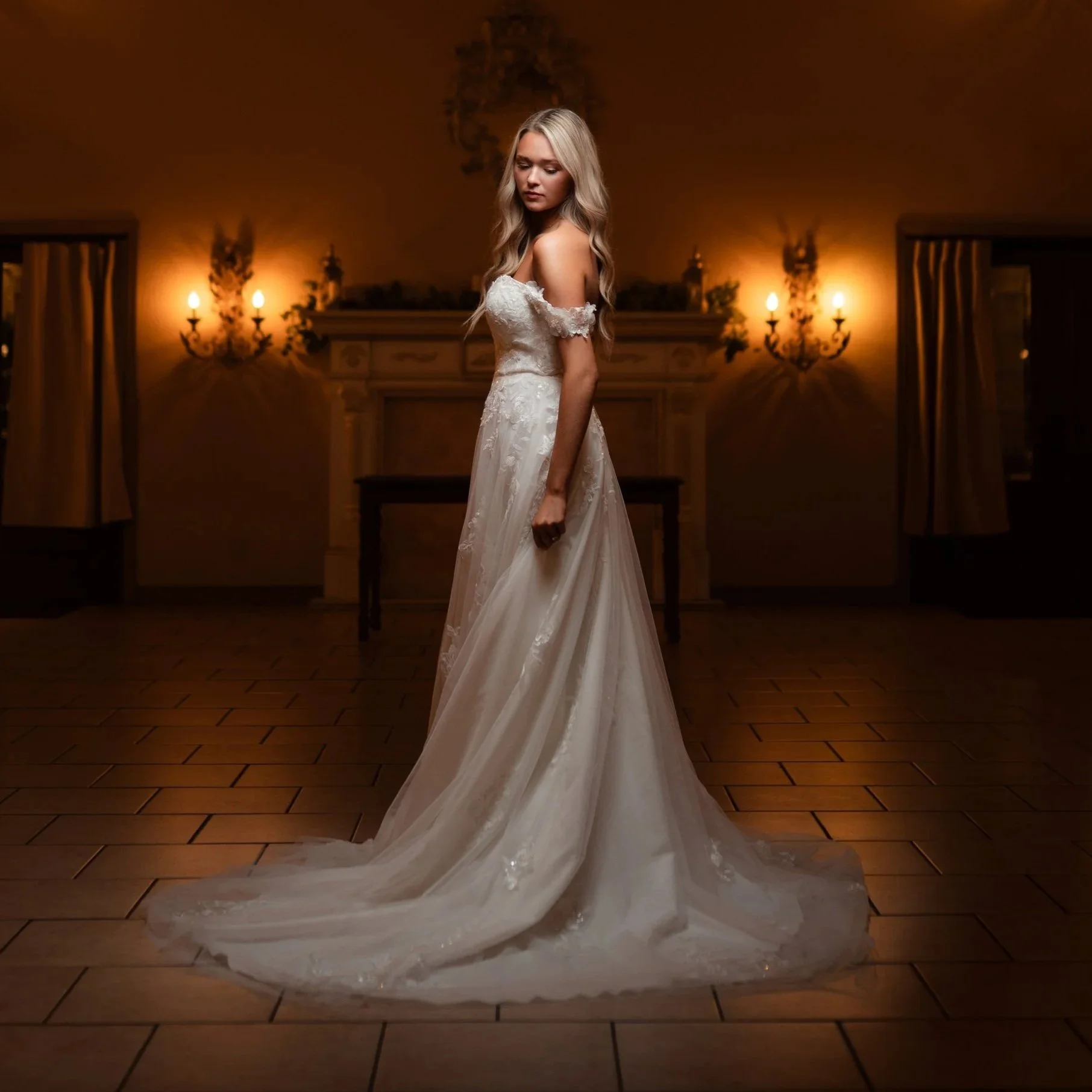 Castle at Wildwood Gardens wedding photography, vintage wedding dress with an off-the-shoulder lace bodice and long flowing skirt stands in a dimly lit room