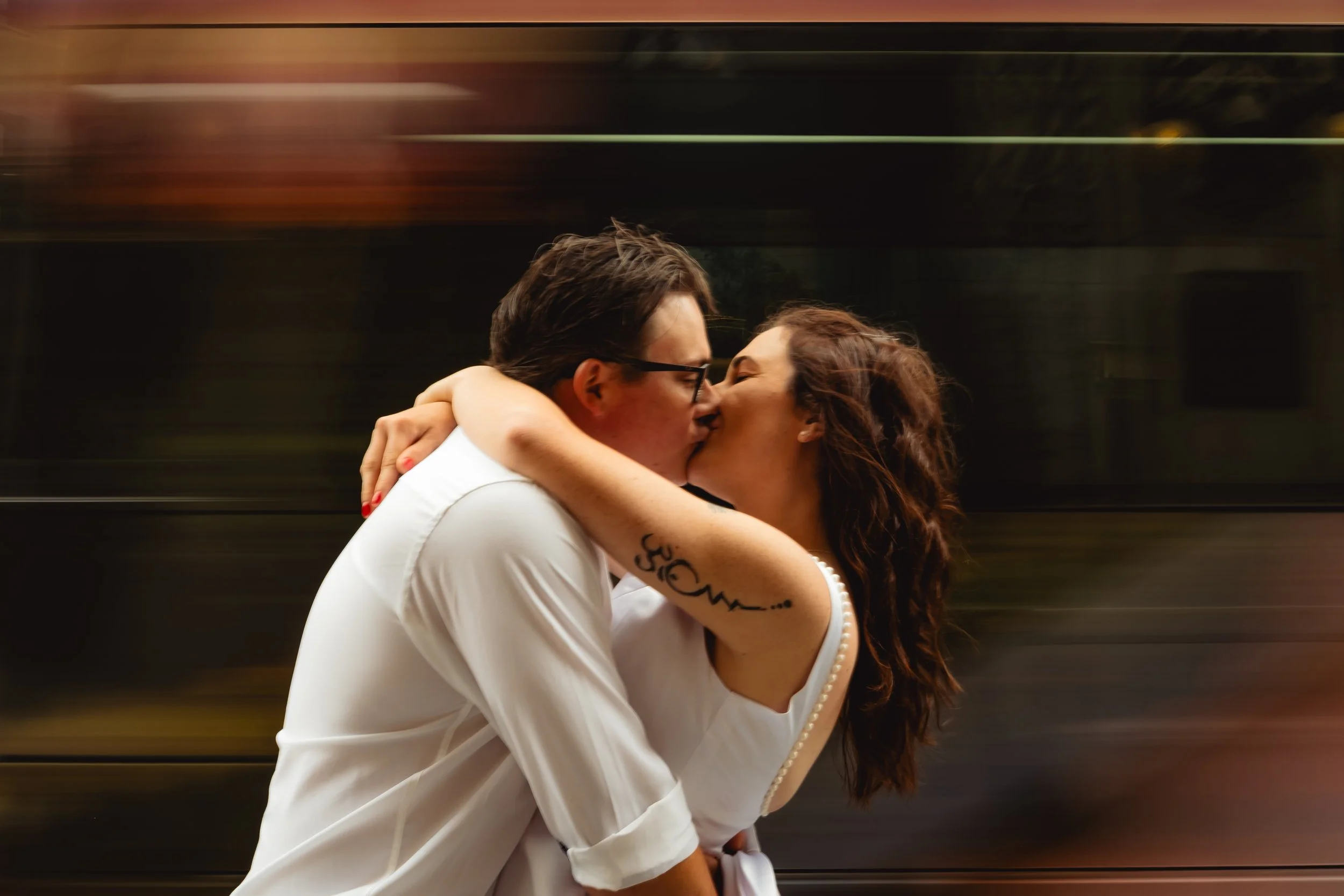 A couple passionately kissing in front of a moving train.