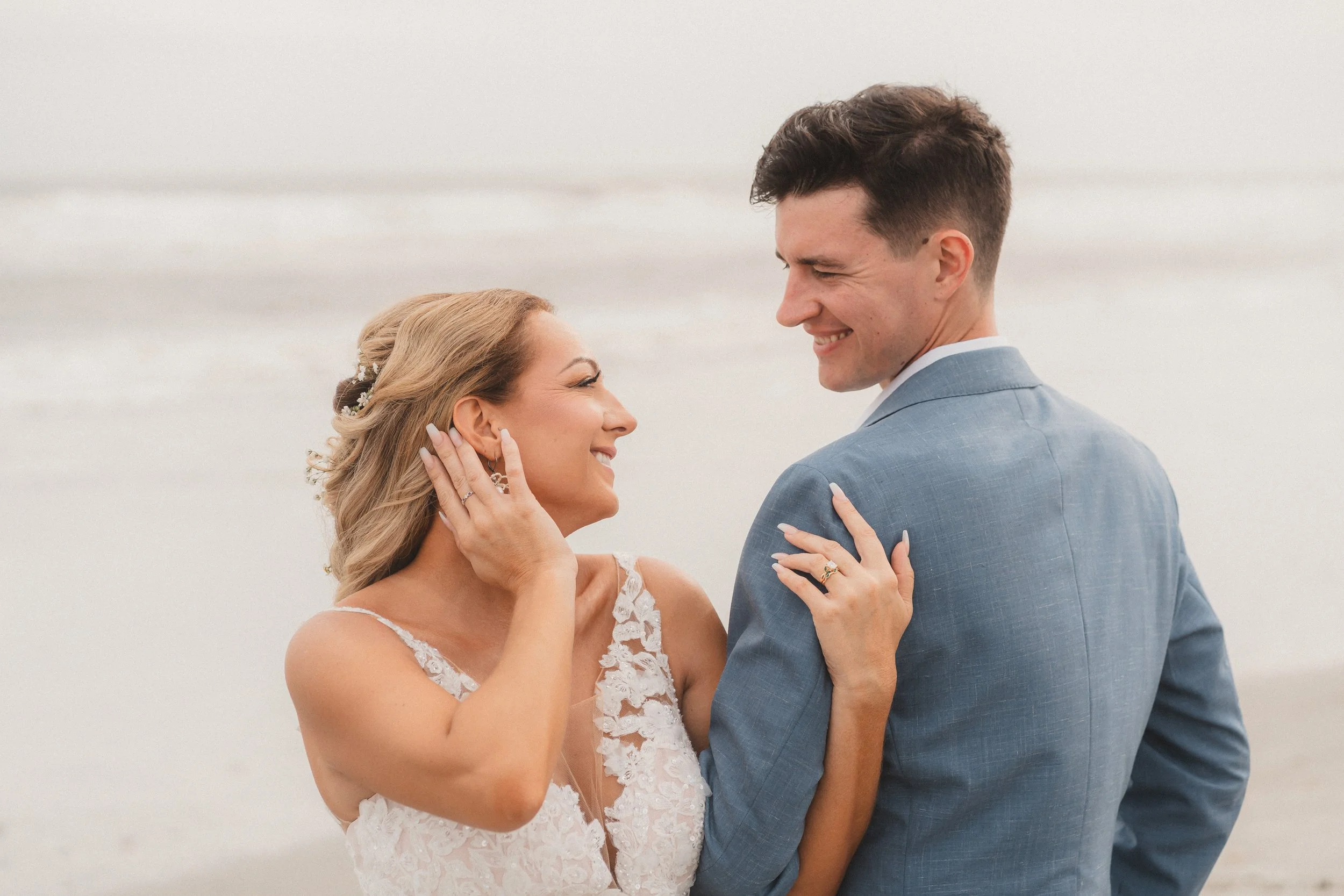 South Carolina beach wedding with bride and groom smiling at each other, with the bride gently touching the groom's shoulder.