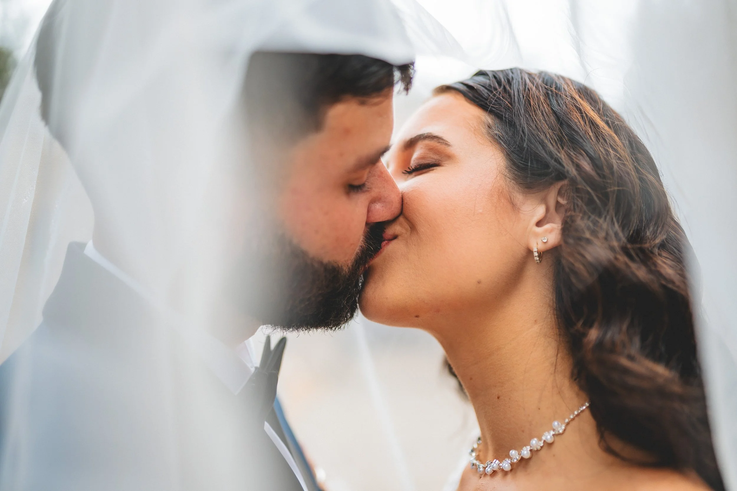 A bride and groom share a kiss under a white veil, Carrollton, GA weddings