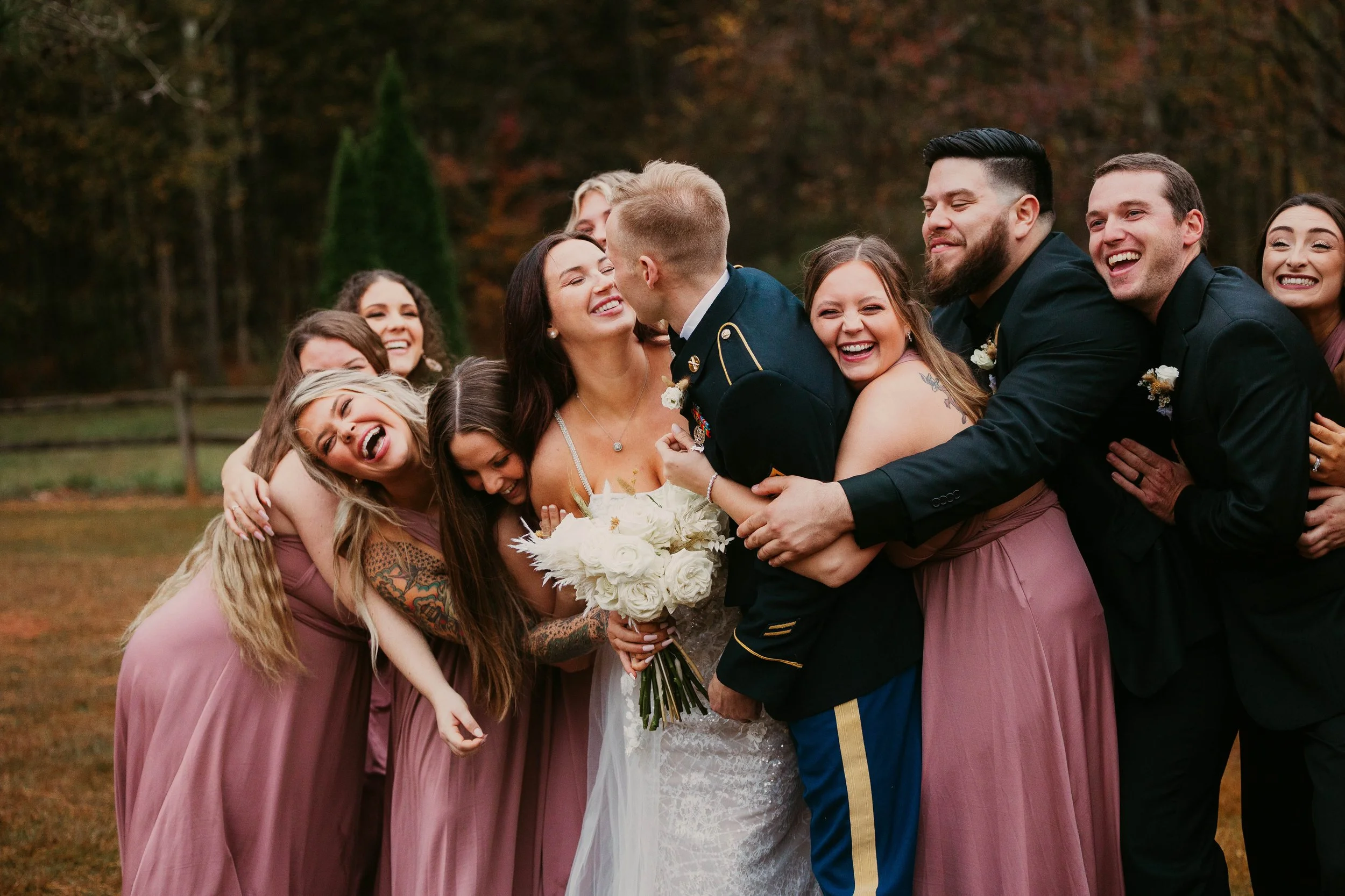 Military wedding photographer, wedding party celebrating and hugging bride and groom, moody rainy wedding day photos