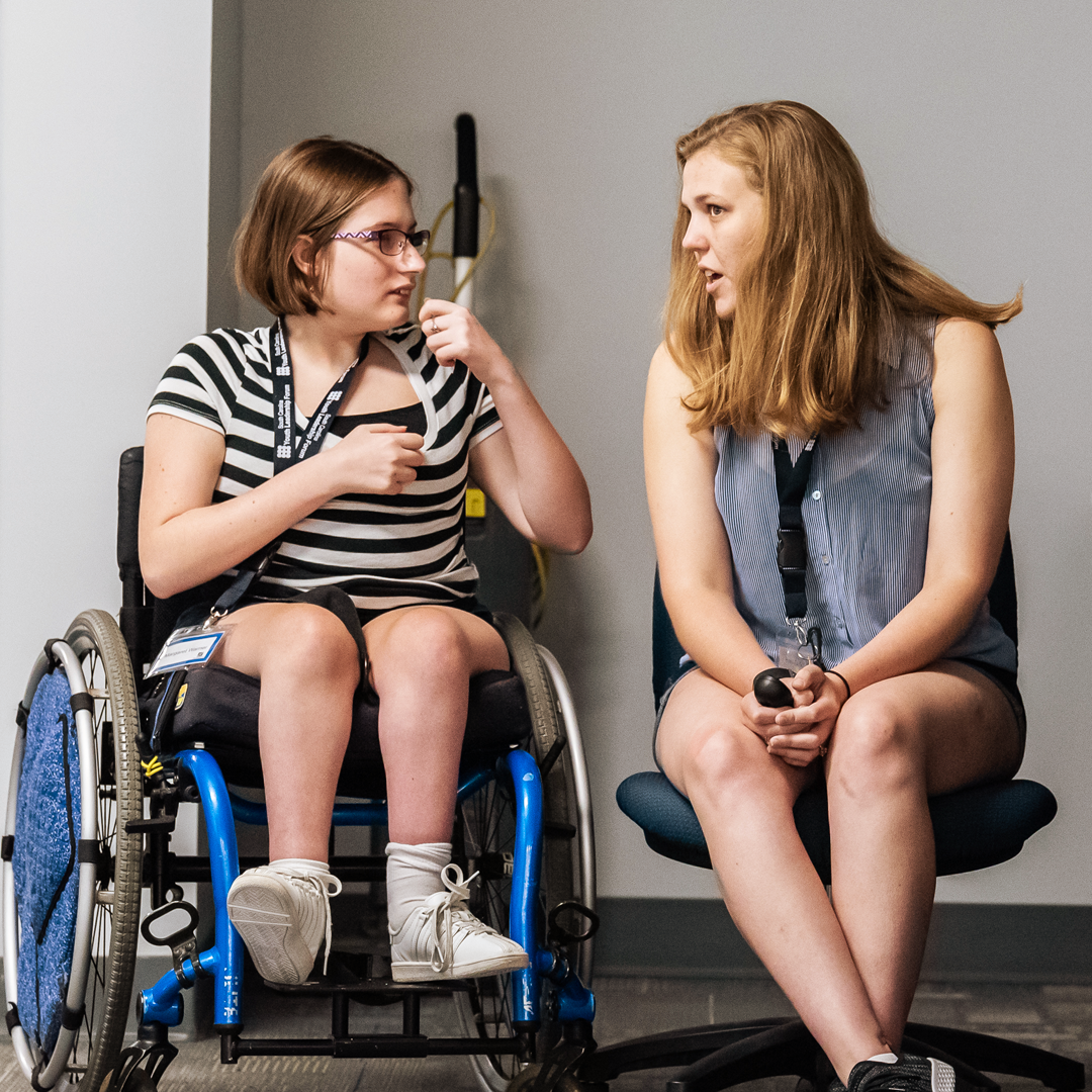 A delegate in a wheelchair looks to YLF staffer Anna Cathryn as they talk.