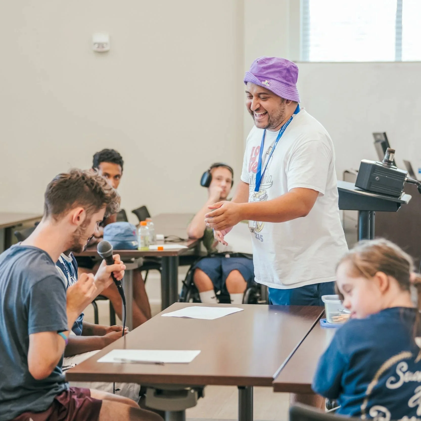  SCYLF leader laughs while a delegate singing into a microphone during a music lesson. 