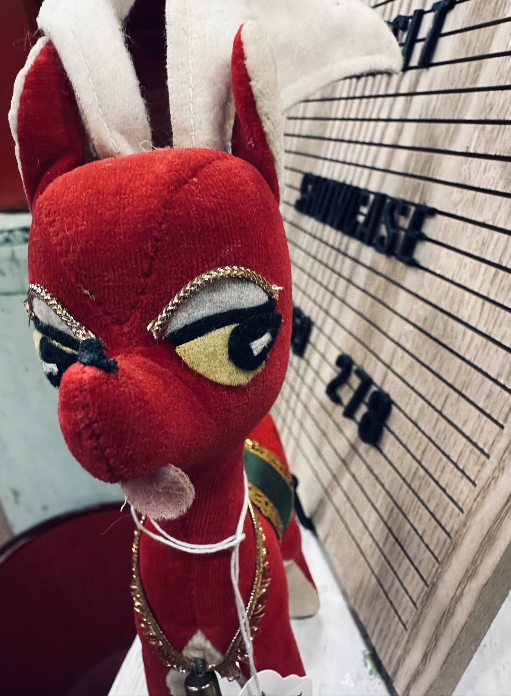 side eye from a red antique mall reindeer with its tongue sticking out.