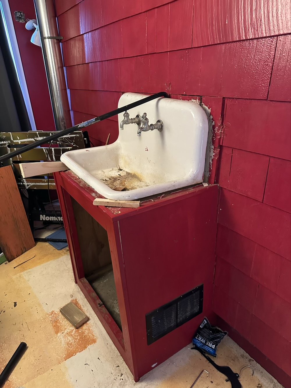 sink against red wall with crowbar sticking out the top