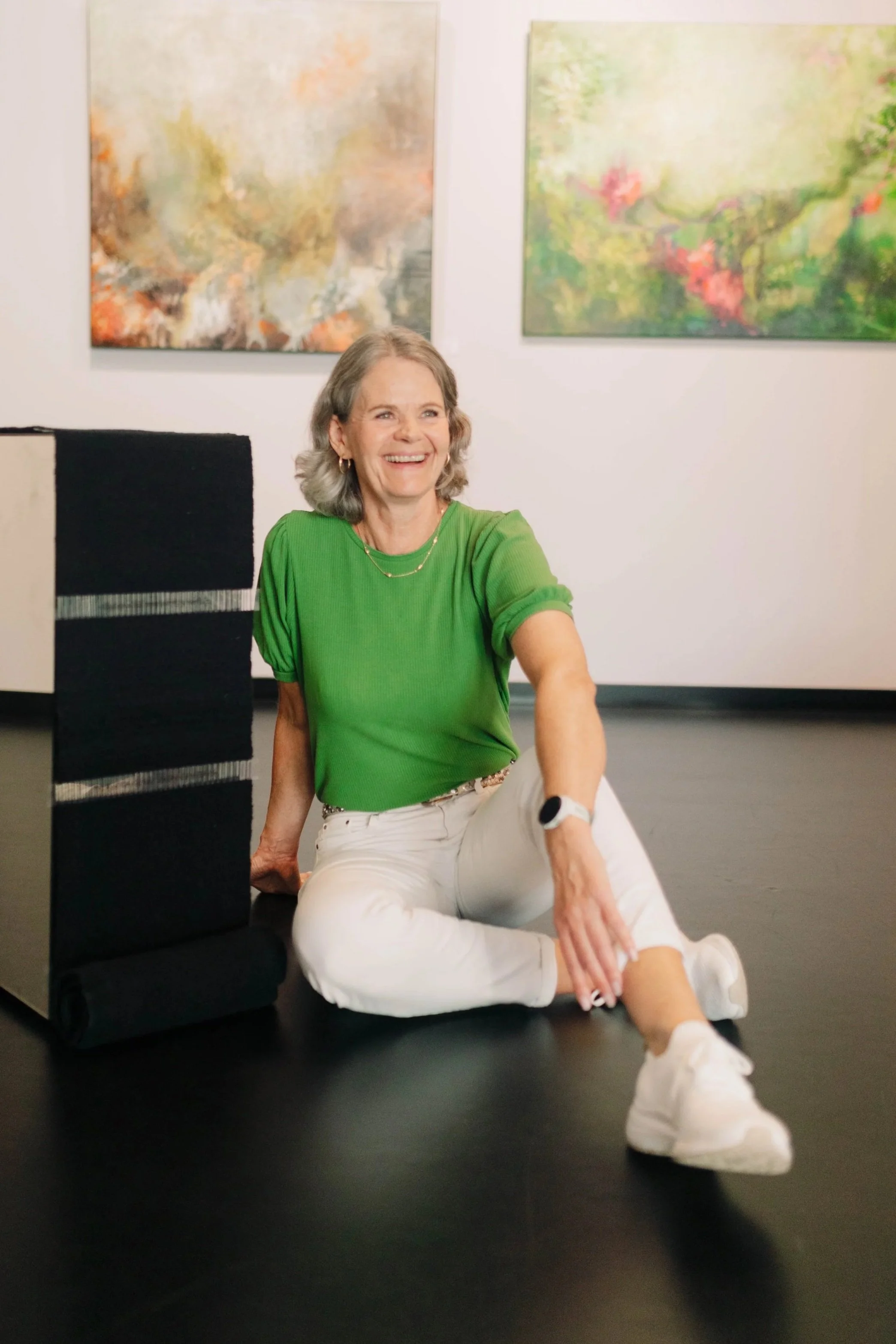 Gro Moe sitter på galverigulv omgitt av abstrakte malerier.