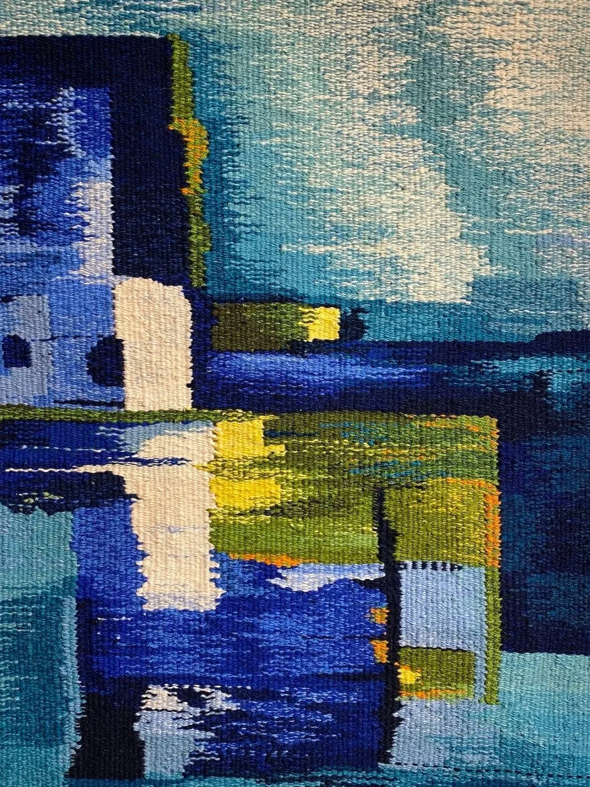 Håndvevd billedvev av Gro Moe med bymotiv i blått, grønt og gult med vannrefleksjoner