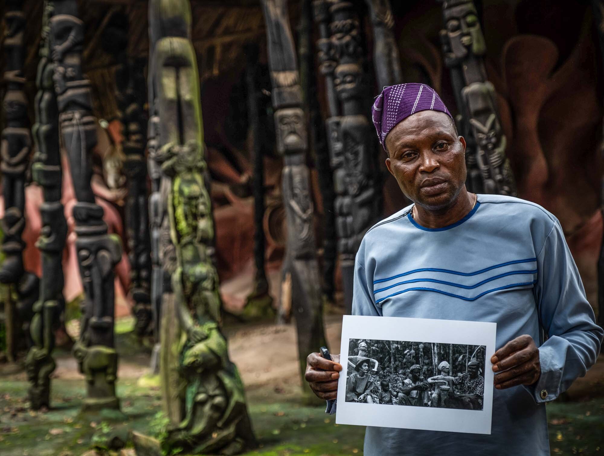  Local artist and conservator Nuredeen Akanji with a photo showing Susanne Wenger, himself as a child and his father Adebisi Akanji 