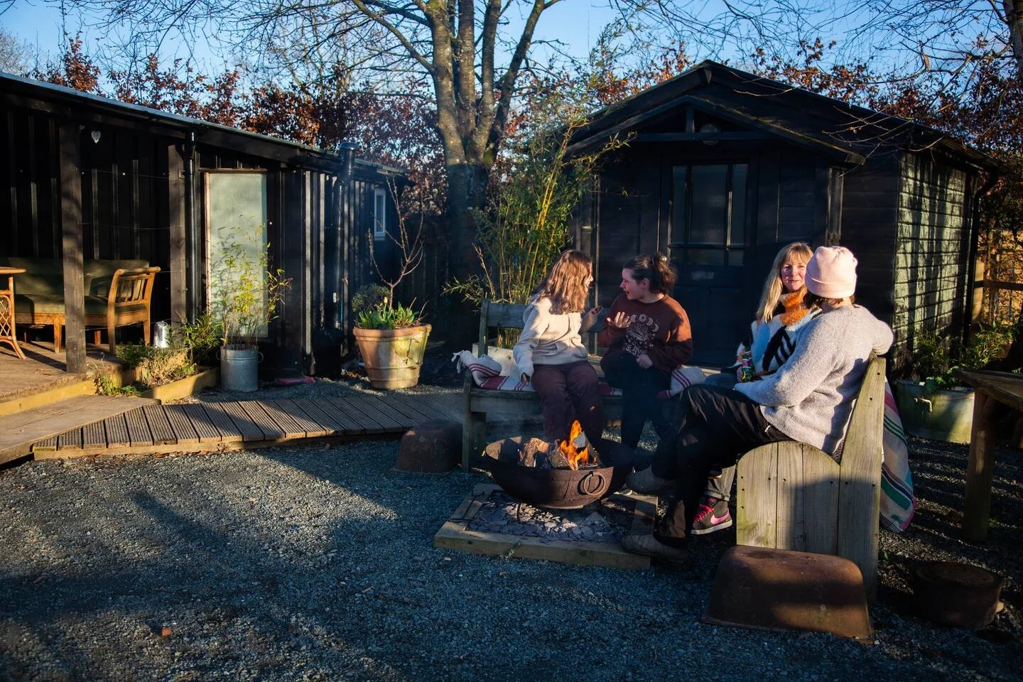 Friends gathered around a fire pit outside at The Deckhouse holiday cottage.