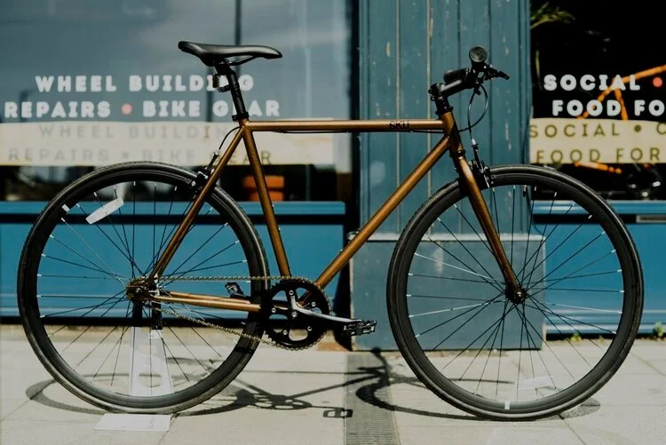 A brown bicycle parked outside a storefront with blue window frames.