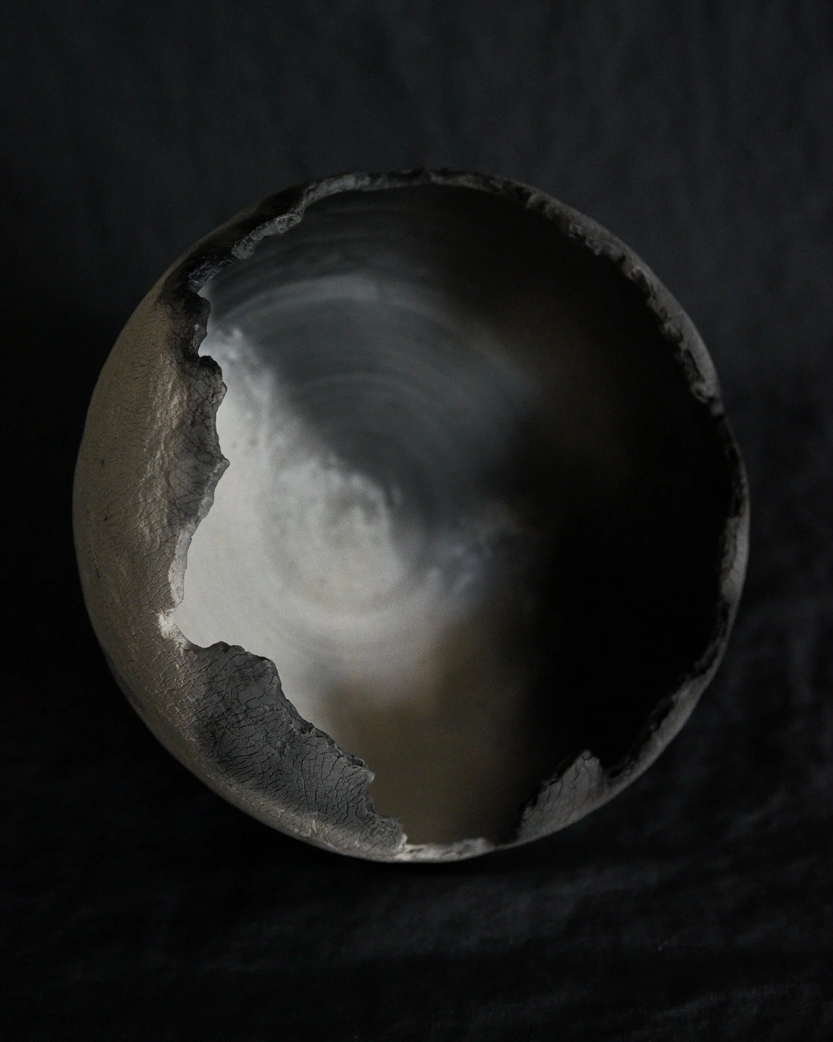 Close-up of a broken, metallic pipe with sharp, jagged edges against a black background.