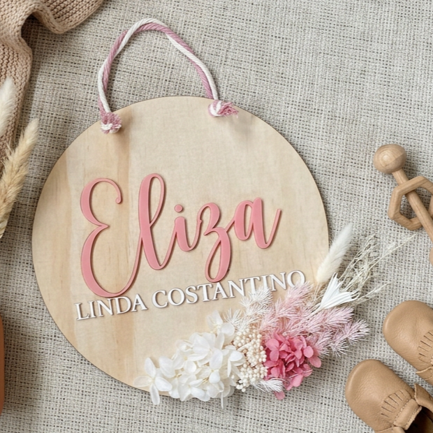 Personalised round timber plaque with pink name lettering and white preserved flowers