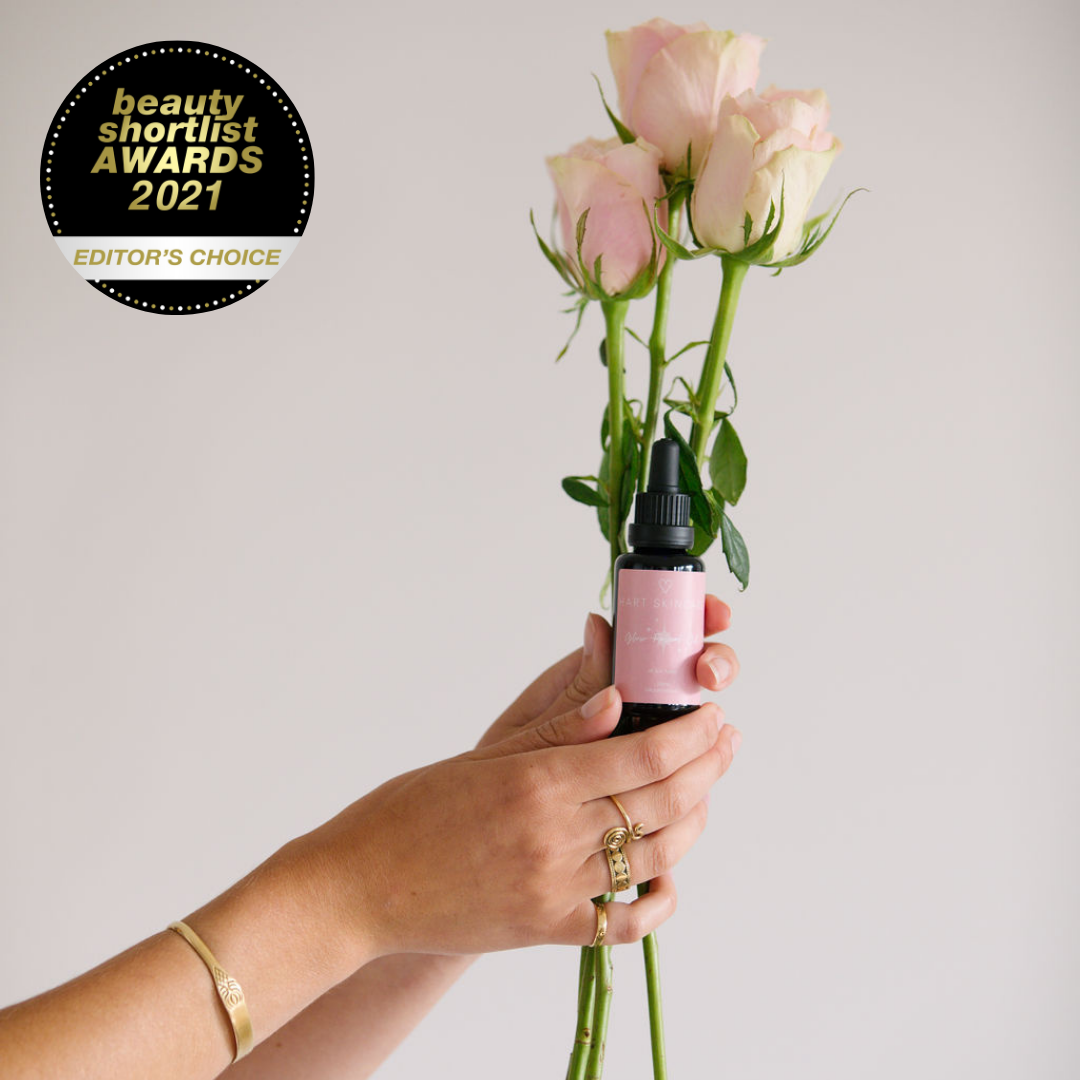 Hands holding pink roses and glow facial oil