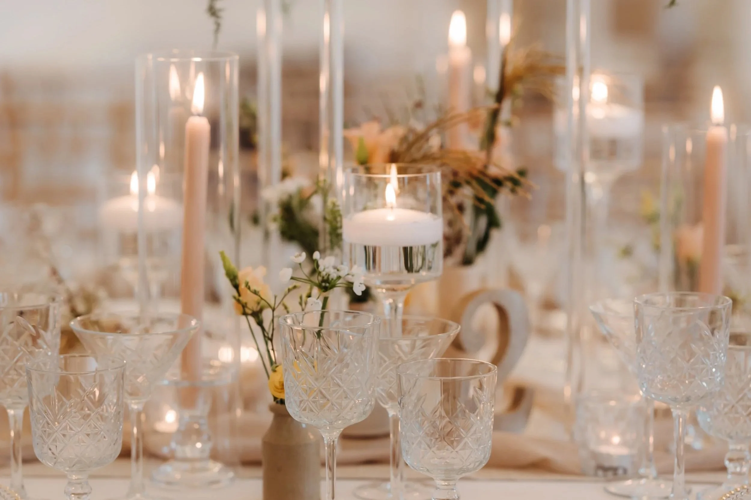 Wedding table set up with ornate glassware and peach coloured candles.