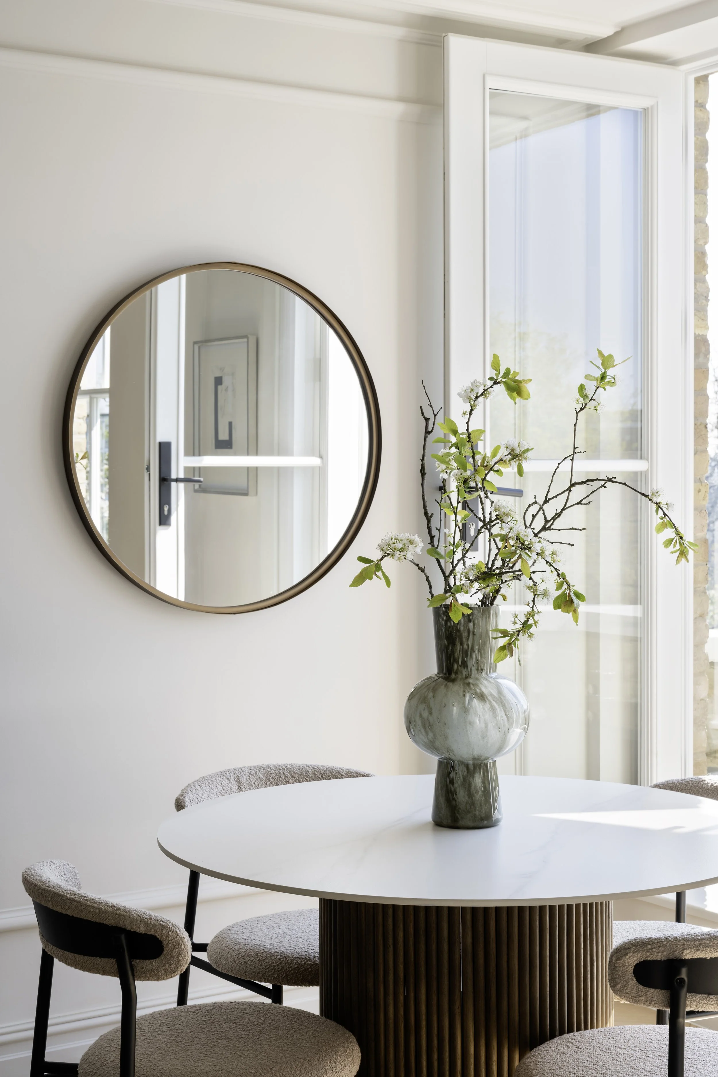 Round dining table styled with artwork, flowers and accessories for the Ealing home staging development, by Decor No5.