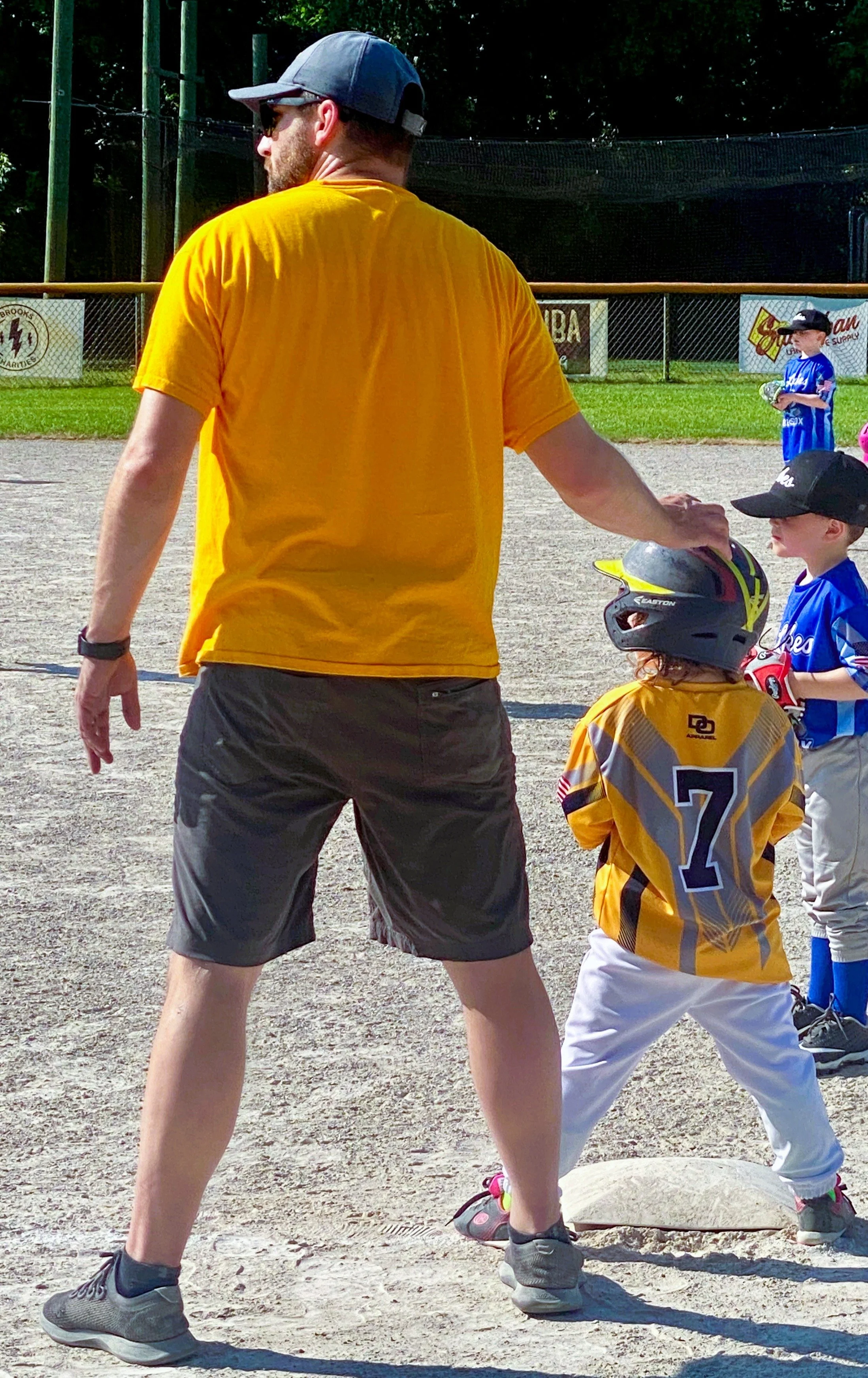 Peter standing, facing away from camera with a small child in a T-ball uniform