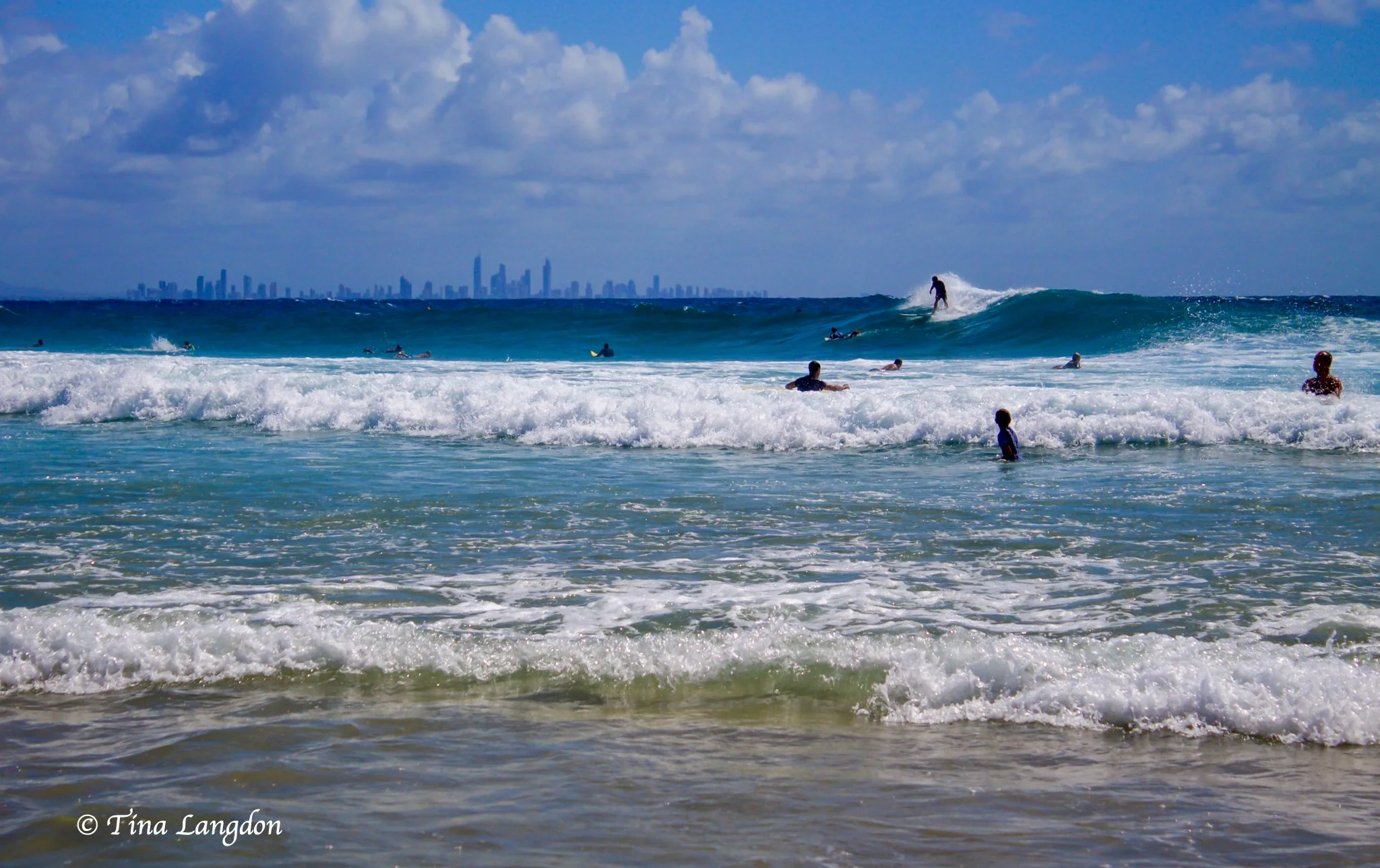 Surfers enjoying the Coral Sea incoming waves with Surfers’ Paradise on the horizon