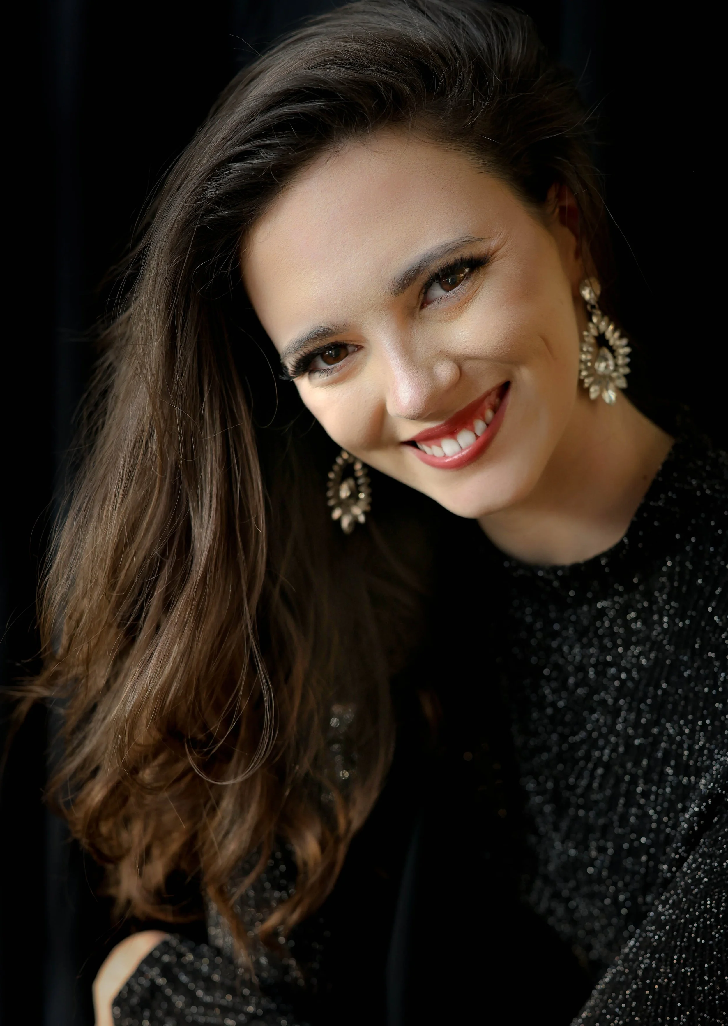 Portrait of a person in a yellow dress with puffed sleeves, smiling at the camera, against a plain background.