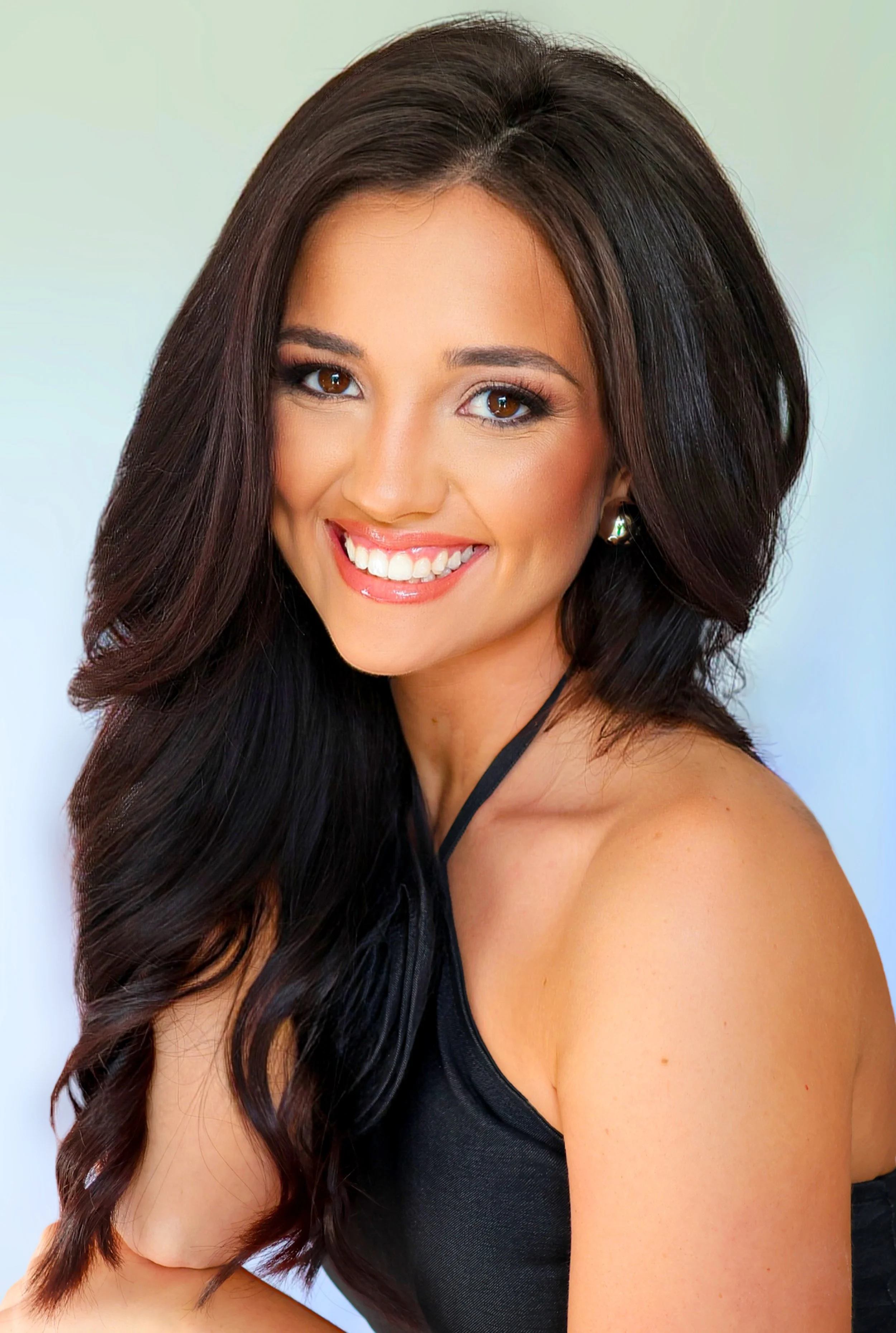 Smiling woman with long blonde hair, wearing blue earrings and a blue dress.