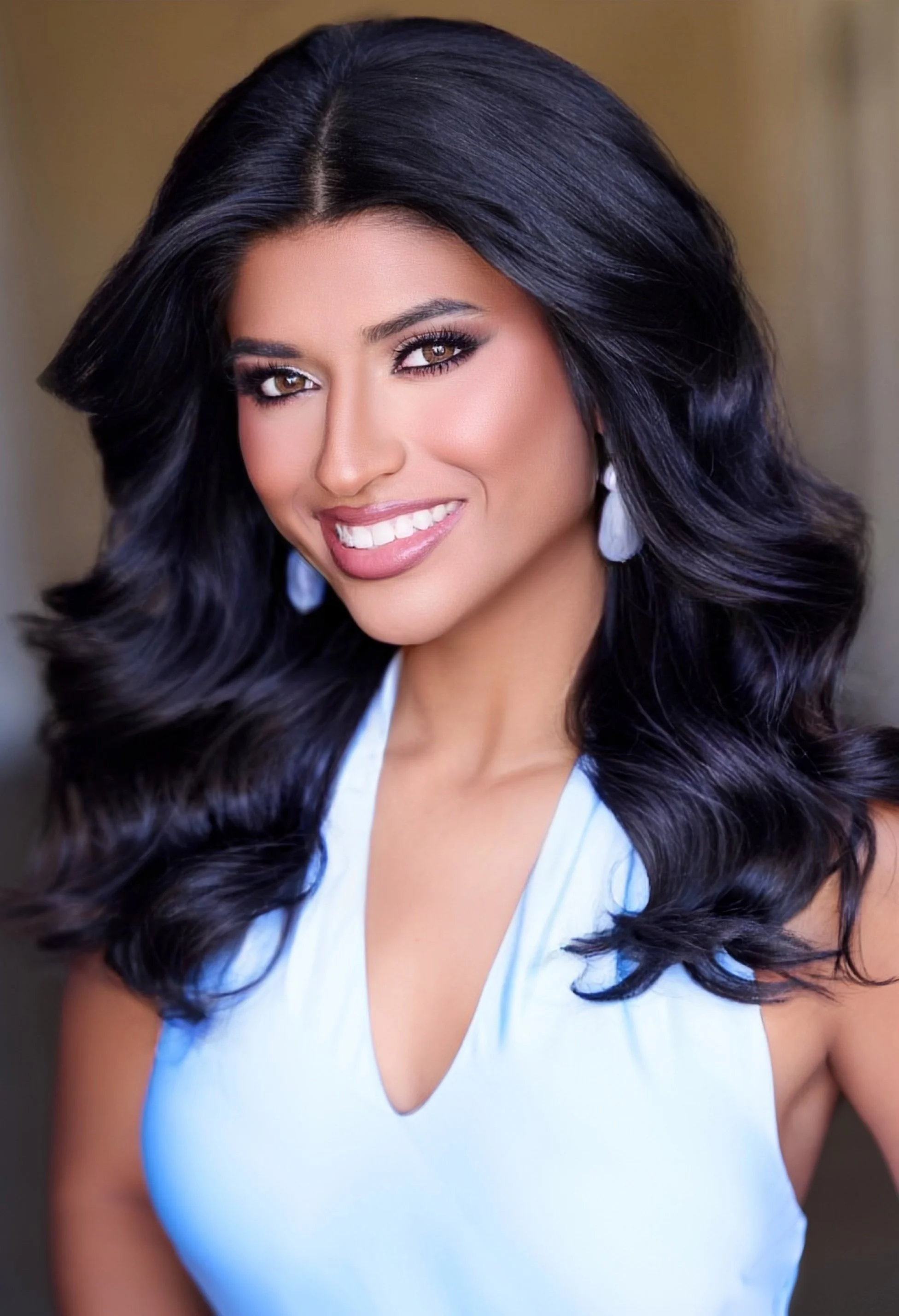 Portrait of a person with long blonde hair, wearing a dark top, against a light background.