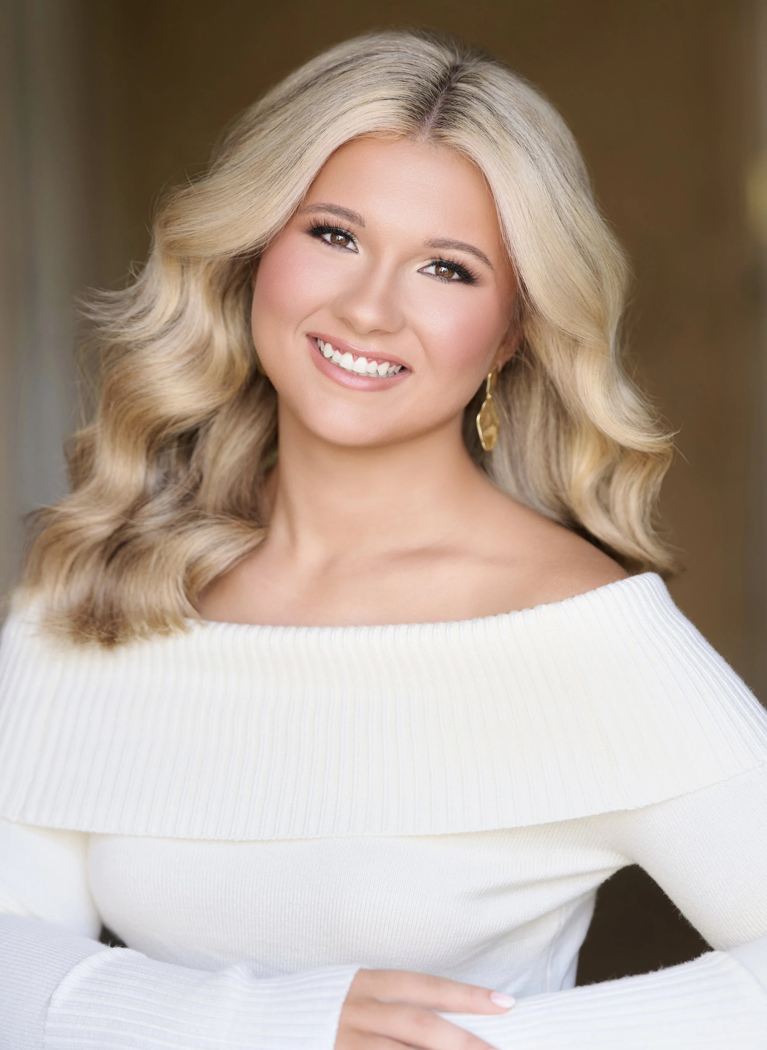Smiling woman with long dark hair wearing a white top and bracelet