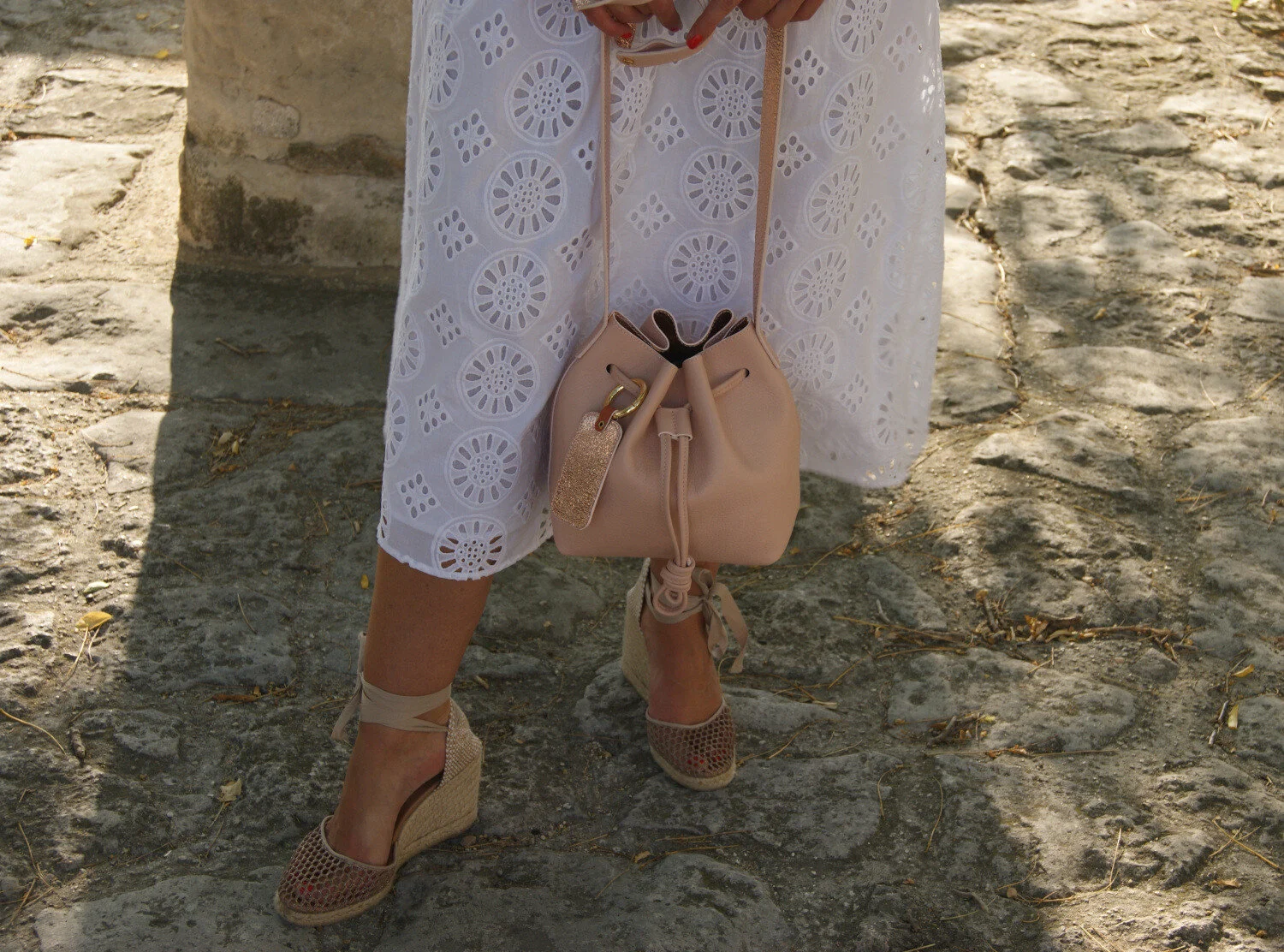 petit sac mini seau cuir rose porté avec robe dentelle blanche