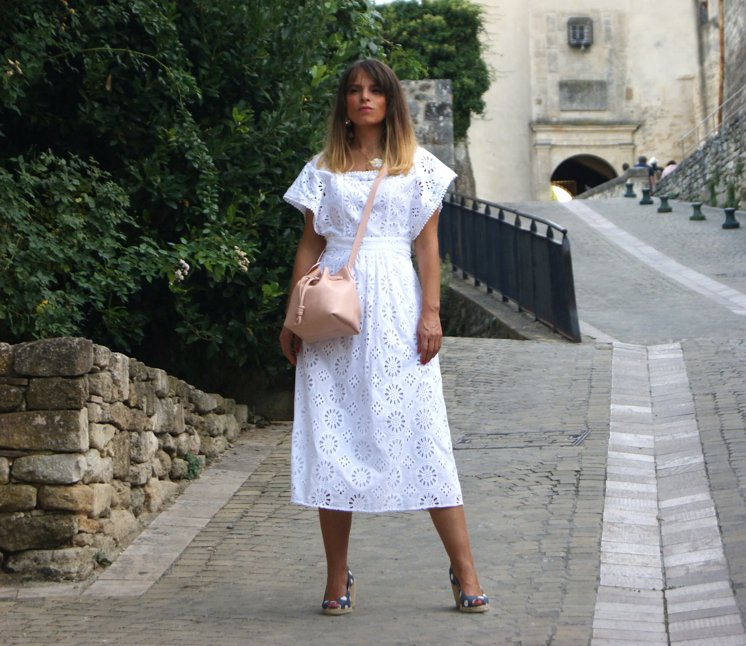 petit sac mini seau cuir rose porté avec robe dentelle blanche