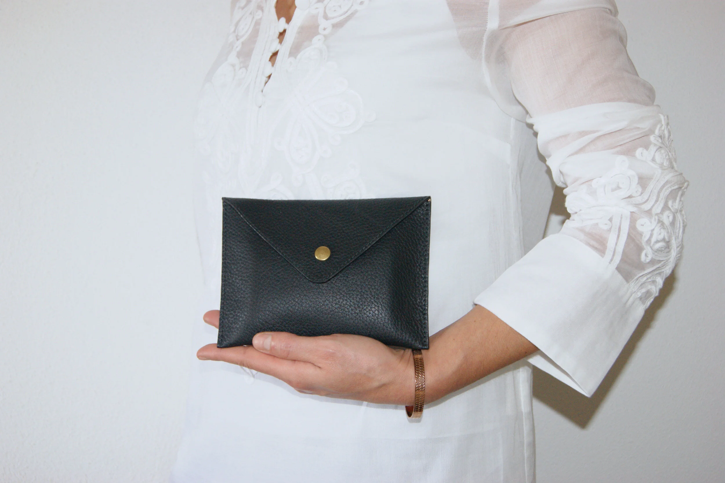 petite pochette cuir grainé noir intérieur métallisé rose gold portée main