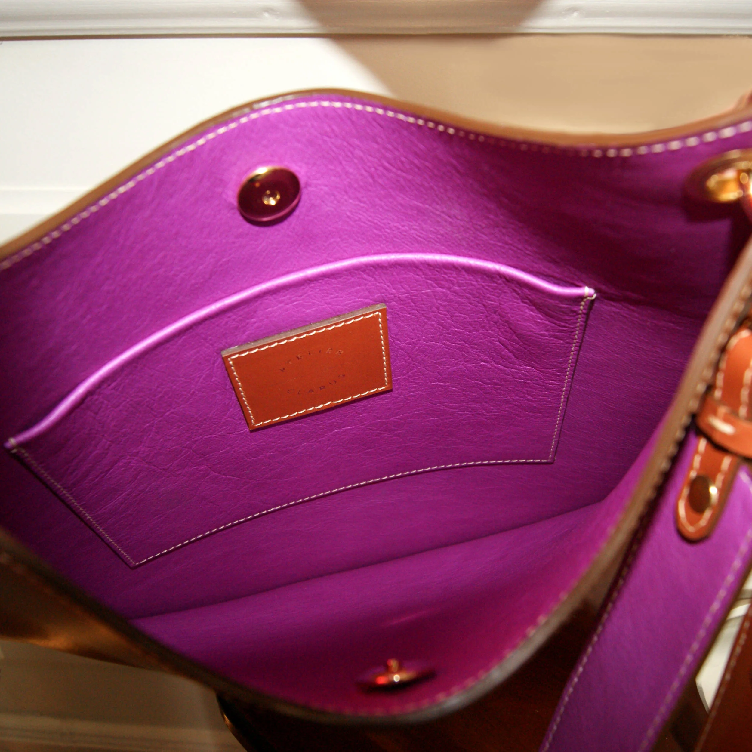 sac plat en cuir lisse gold intérieur cuir fushia bijouterie dorée une anse et une bandoulière vue intérieur du sac